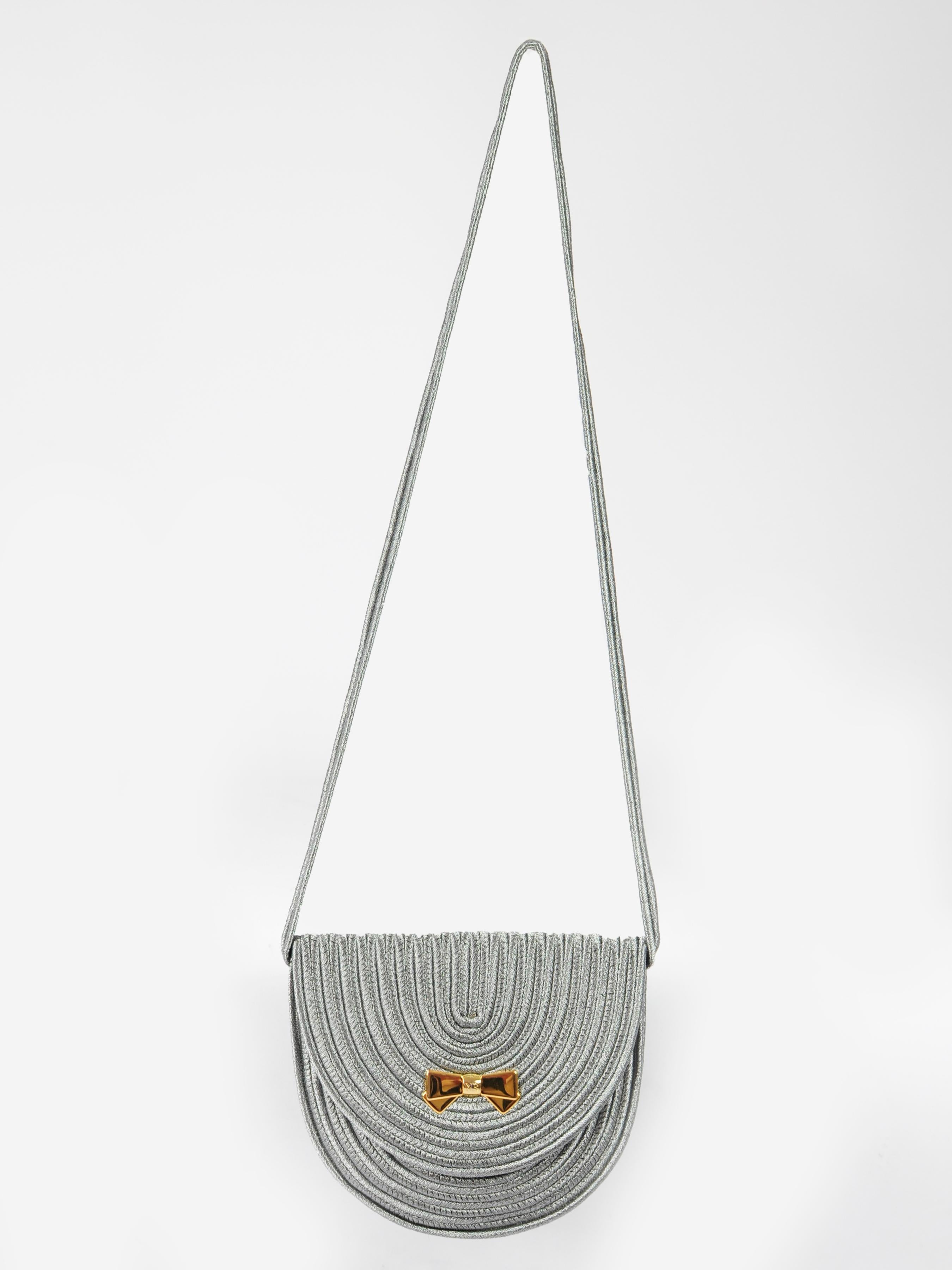Nina Ricci Passementerie Bag from the 1980s in metallic silver with signature golden Nina Ricci bow shaped closure. Passementerie, a technique very known for it’s use in Yves Saint Laurent designs, is also a Nina Ricci favorite. The bag can be worn