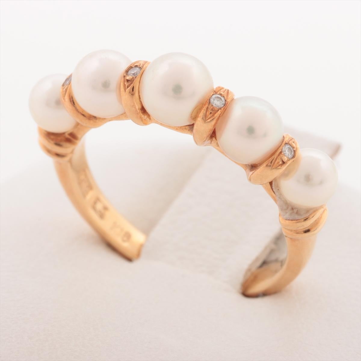 The Nina Ricci Pearl Diamond Ring is an exquisite piece that blends classic elegance with a touch of contemporary glamour. Featuring five lustrous pearls set in a beautifully crafted band, the ring is adorned with four small diamonds that add a