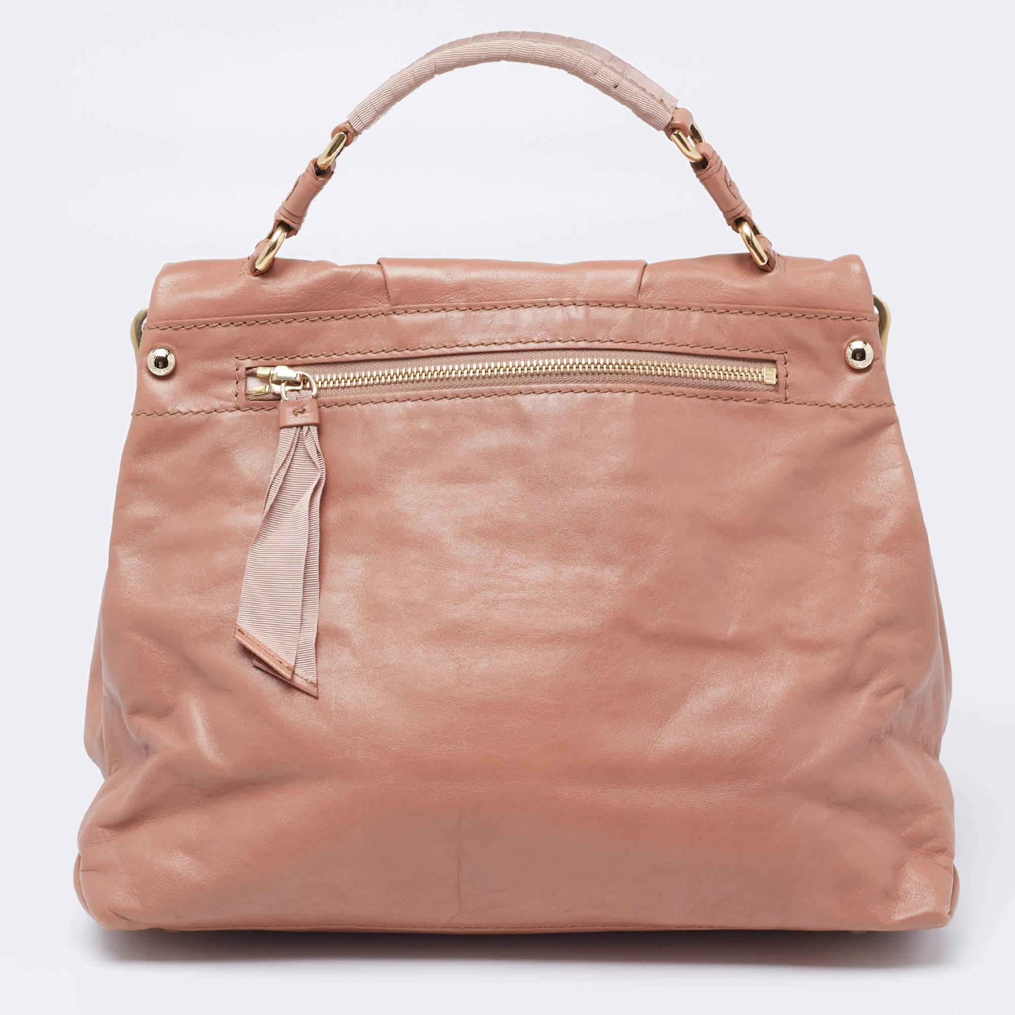 Make a striking appearance with this fashionable Liane bag by Nina Ricci. It is crafted from rose beige leather and fabric, with a sturdy handle perched on the top. This bag is completed with gold-tone hardware and a roomy canvas-lined interior. Say