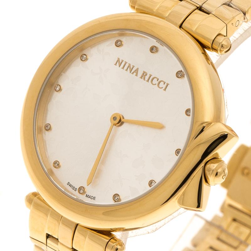 Perfect to assist you and enhance all your chic ensembles, this Nina Ricci watch comes beautifully crafted from gold-plated stainless steel. It features a silver dial with floral details, diamond hour markers and two sword-shaped hands. The quartz