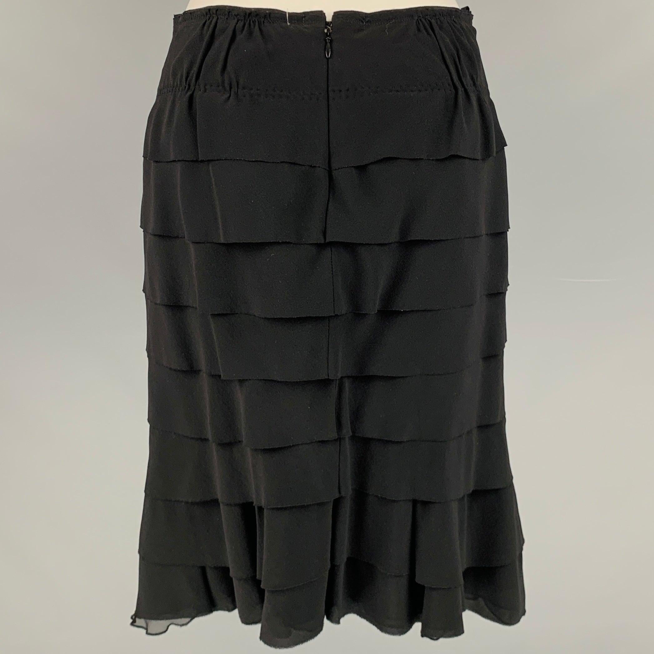 NINA RICCI skirt in a black silk fabric featuring a pencil style, ruffle design, and back zipper closure. Made in France.Excellent Pre-Owned Condition. 

Marked:   38 

Measurements: 
  Waist: 27 inches Hip: 34 inches Length: 22.5 inches 
  
  
