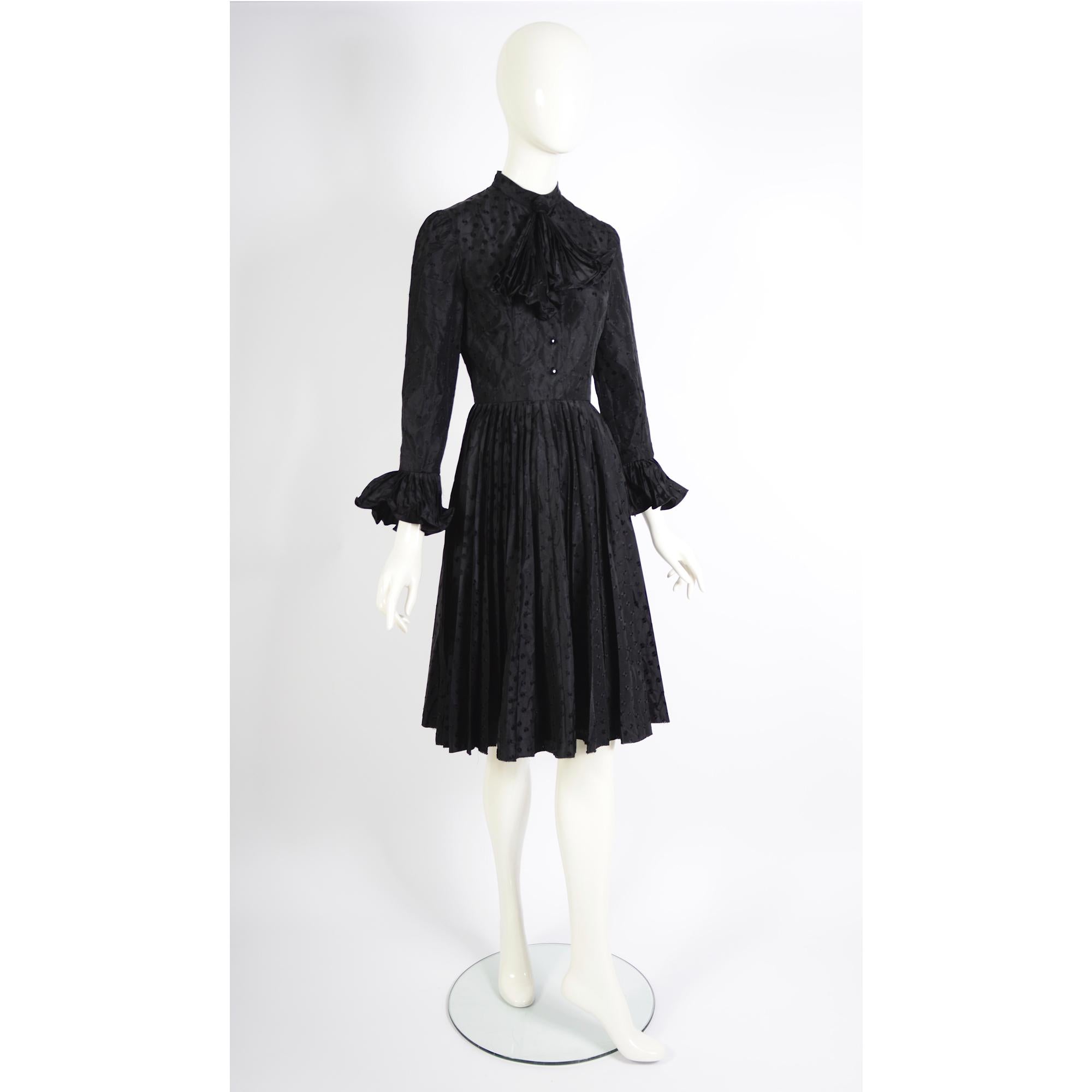 Vintage early 1970s Nina Ricci black silk dress featuring a razor-sharp pleated skirt. The bodice of the dress is lined with silk gauze and closes with black front buttons, complemented by a refined ruffle tie at the neckline.
The polka dots on the