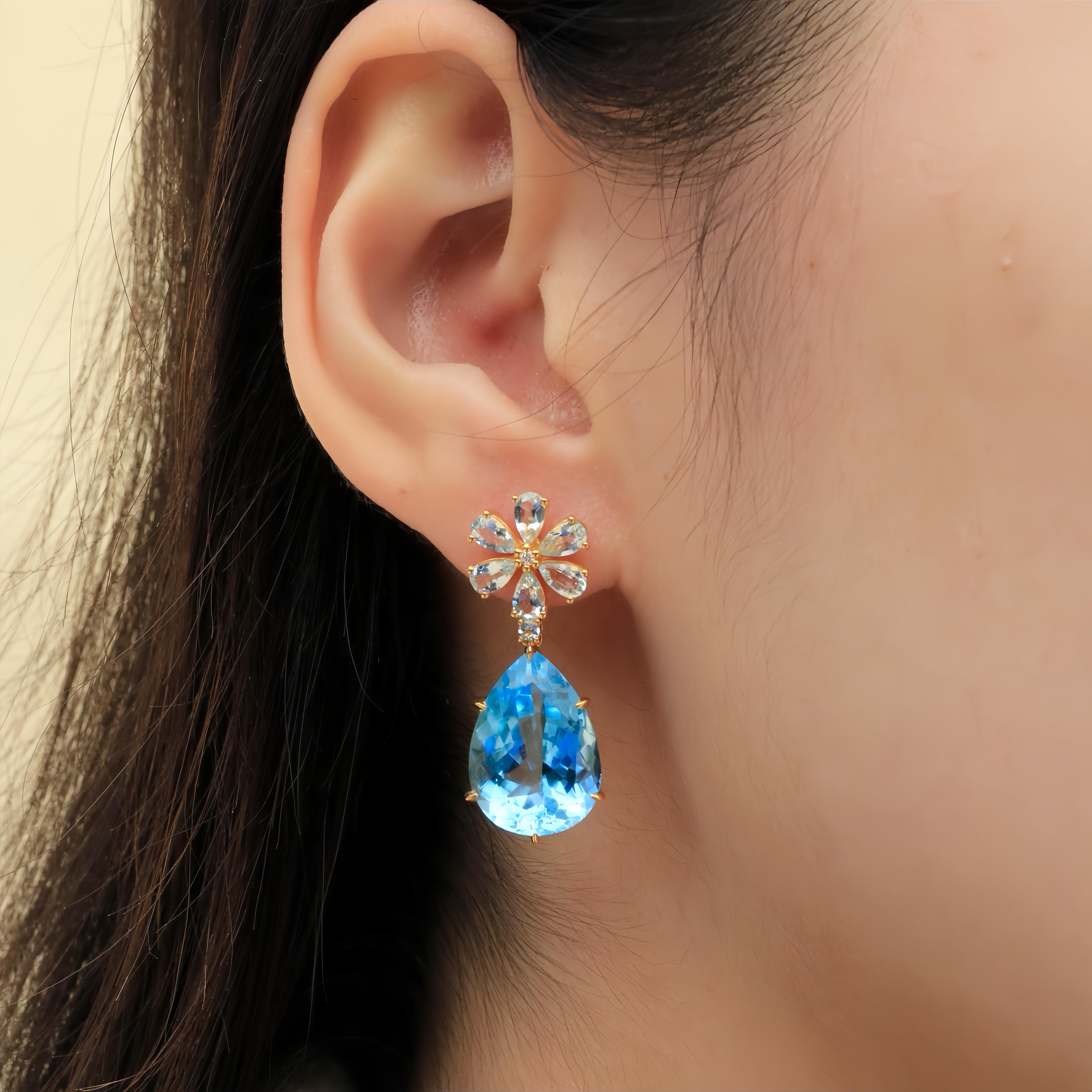 The Aquamarine Diamond Double Blossom Drop Earrings radiate a serene elegance, with sky-blue aquamarines arranged in a charming floral design. Each gemstone is carefully set to reflect its soft, tranquil hue, reminiscent of a clear sky, while the