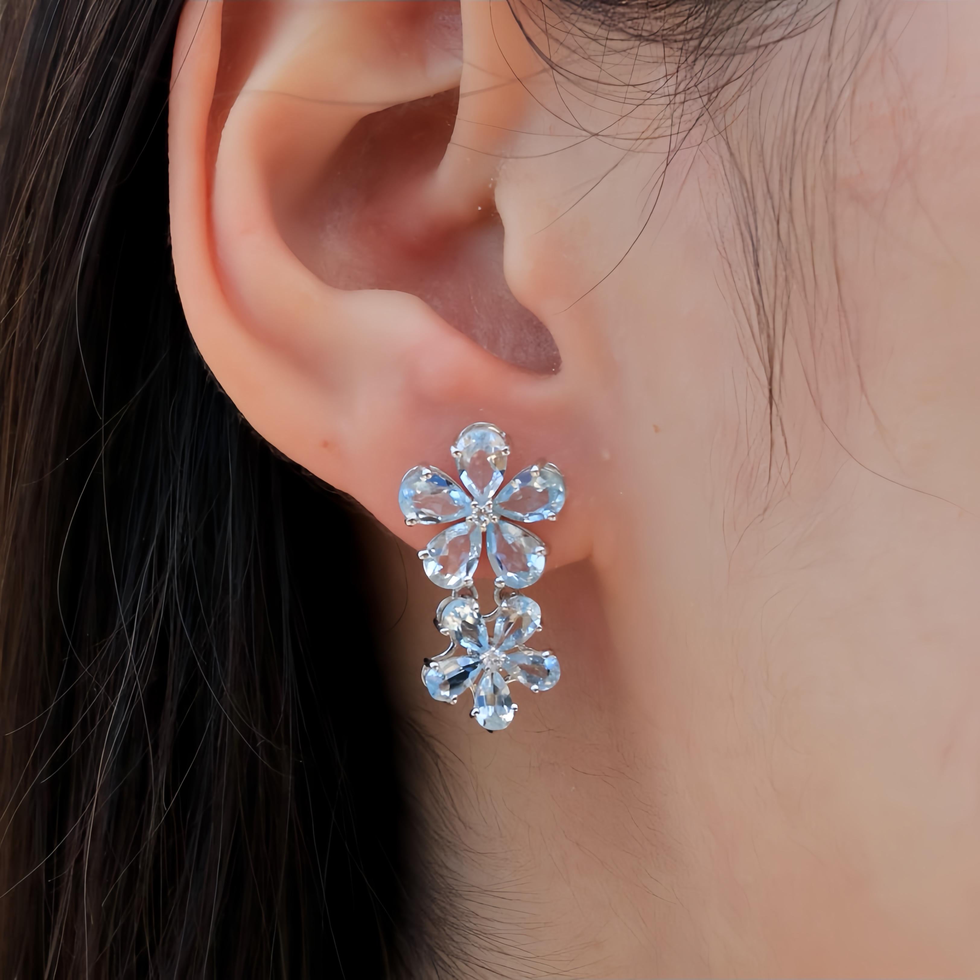 The Aquamarine Diamond Double Blossom Drop Earrings radiate a serene elegance, with sky-blue aquamarines arranged in a charming floral design. Each gemstone is carefully set to reflect its soft, tranquil hue, reminiscent of a clear sky, while the
