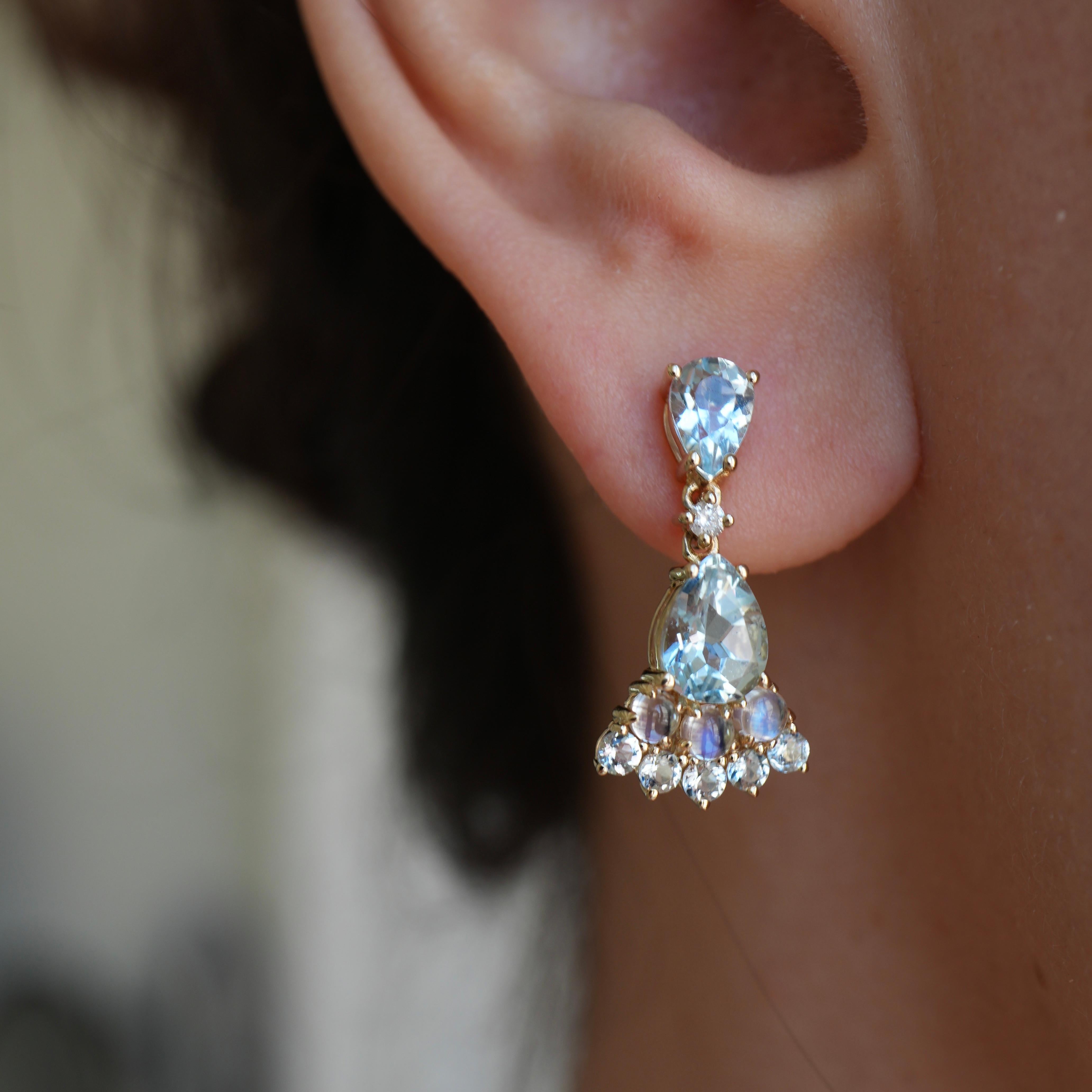 Add a touch of ethereal beauty to your look with the Nina Zhou Aquamarine Moonstone Diamond Earrings. These elegant earrings, set in luxurious yellow gold, feature pear-shaped aquamarines that capture the light with a serene, oceanic blue. The