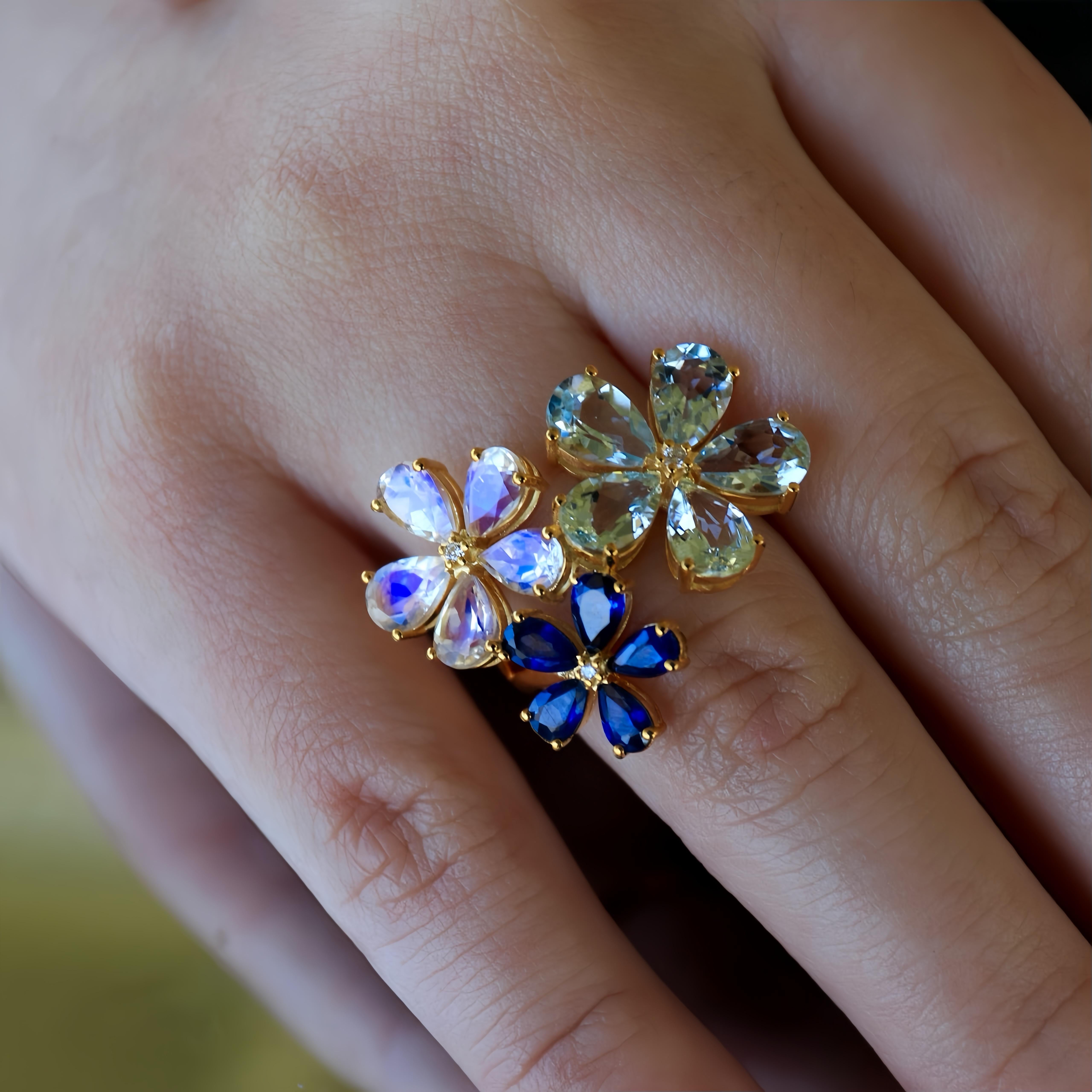 Discover the Nina Zhou Aquamarine Moonstone Sapphire Diamond Flower Blossom Ring, an enchanting work of art that showcases the brilliance of aquamarine, the mystical beauty of moonstone, and the deep allure of sapphires. Crafted in luxurious 14k