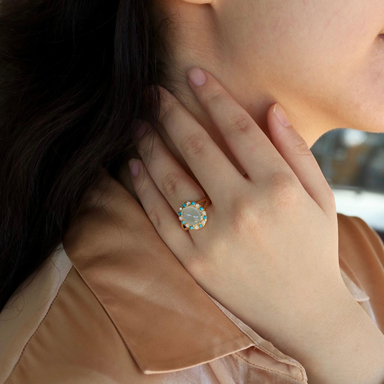 Radiating timeless elegance, the 3.14 ctw Aquamarine Turquoise Diamond Vintage-Style Cocktail Ring is a masterpiece of color and craftsmanship. At its heart lies a luminous cabochon aquamarine, its serene sky-blue hue reminiscent of tranquil waters.