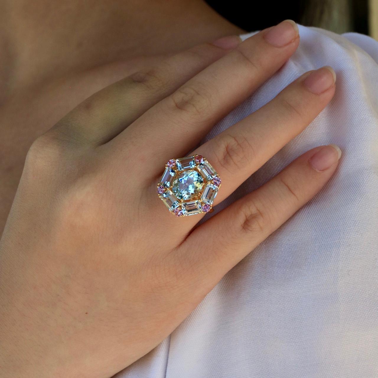 Der Margaret Aquamarine Pink Sapphire Cocktail Ring strahlt Eleganz und Charme aus und ist ein Fest der Farben und der Kunstfertigkeit. In der Mitte schimmert ein atemberaubender ovaler Aquamarin mit der ruhigen Schönheit eines klaren Himmels,
