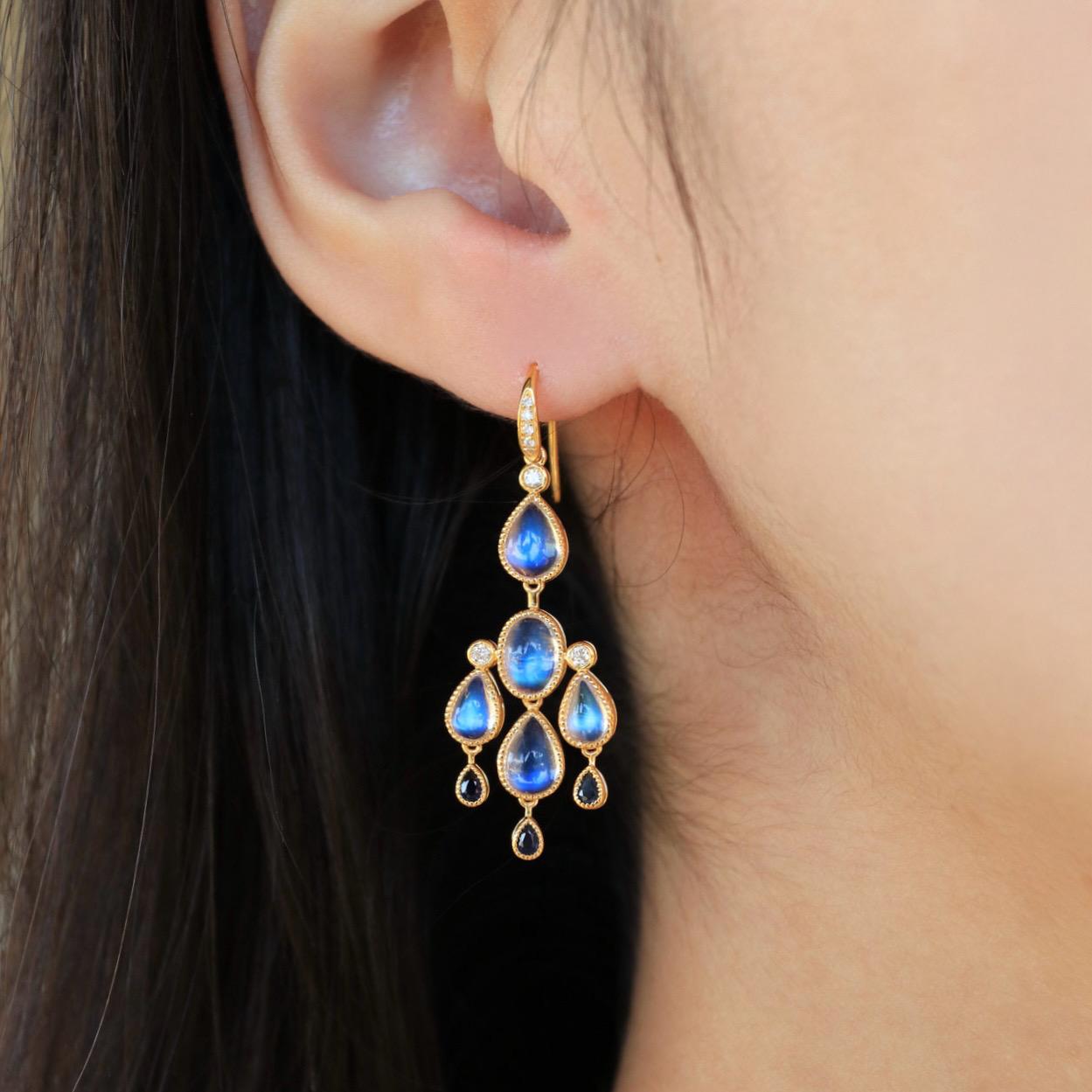 Illuminate your elegance with these Moonstone Sapphire Diamond Chandelier Drop Earrings, a masterpiece that captures the ethereal glow of moonlight. Featuring luminous moonstones framed in 14k yellow gold, their captivating rainbow sheen reflects a