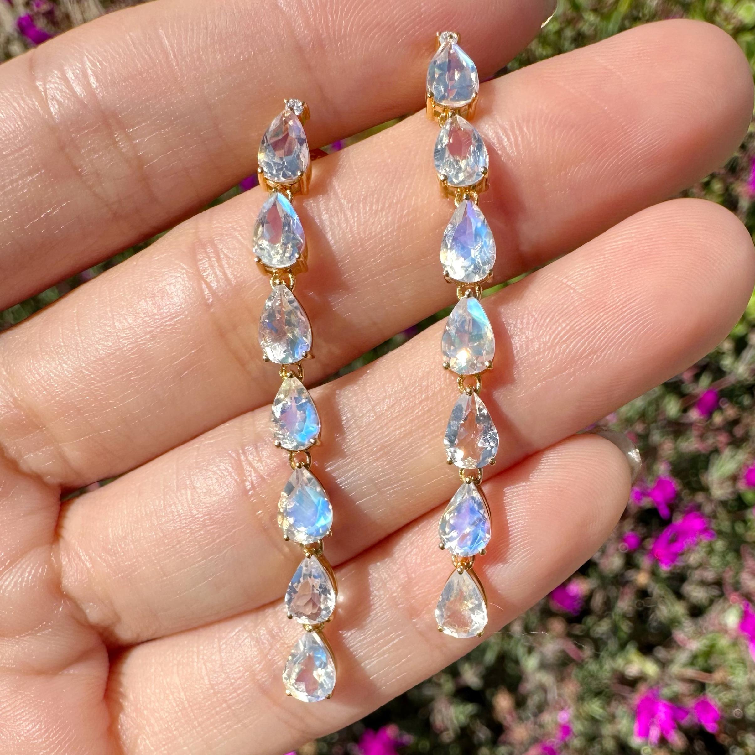 Nina Zhou's Pear Blue Moonstone Diamond Line Drop Earrings in 18k Yellow Gold are a masterpiece of elegance and mystique. Each earring features a mesmerizing pear-shaped blue moonstone, renowned for its captivating luminosity and ethereal blue sheen