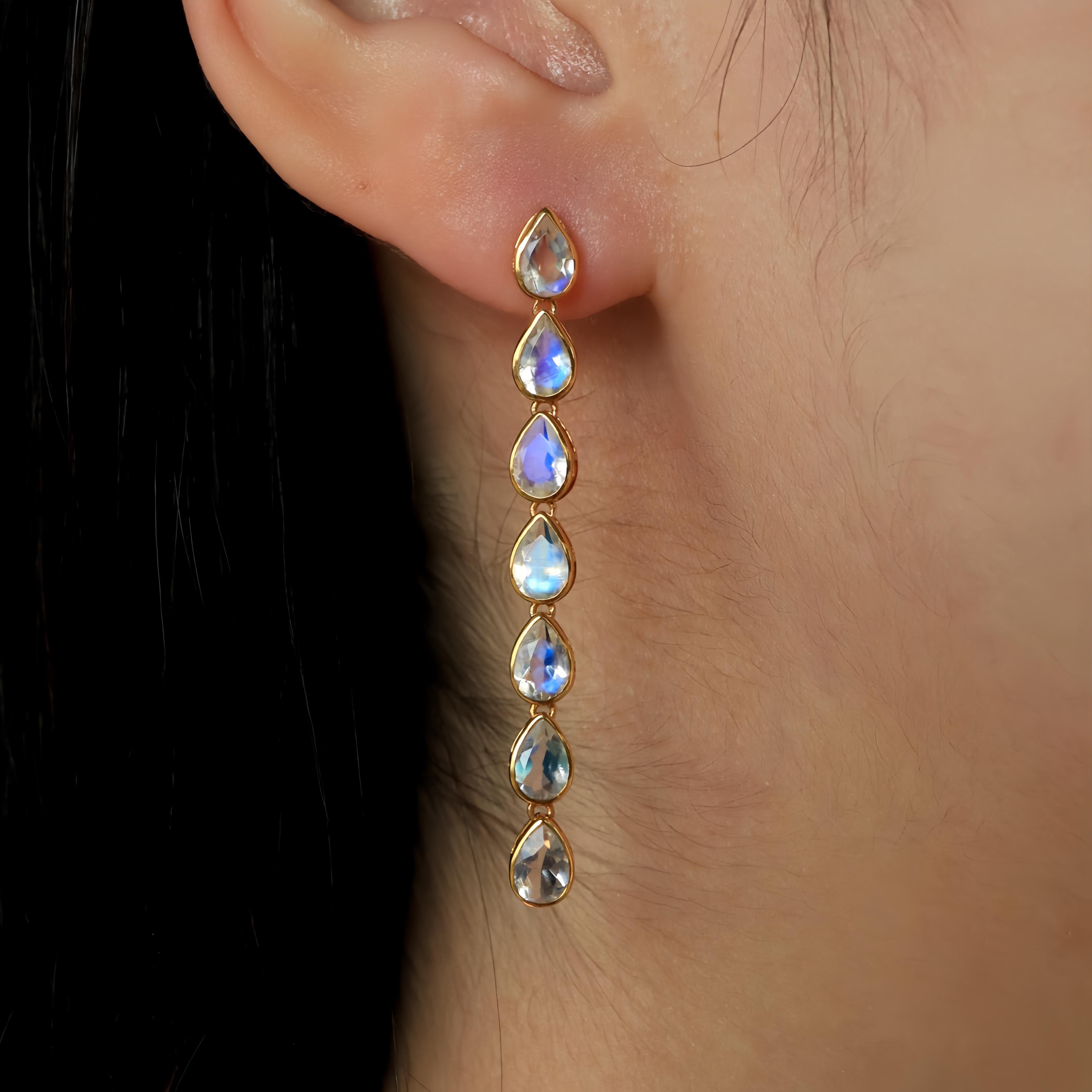 Delve into the captivating elegance of Nina Zhou's Pear Blue Moonstone Line Drop Earrings, masterfully crafted in gleaming 14k yellow gold. These exquisite earrings showcase pear-shaped blue moonstones, celebrated for their ethereal blue glow and