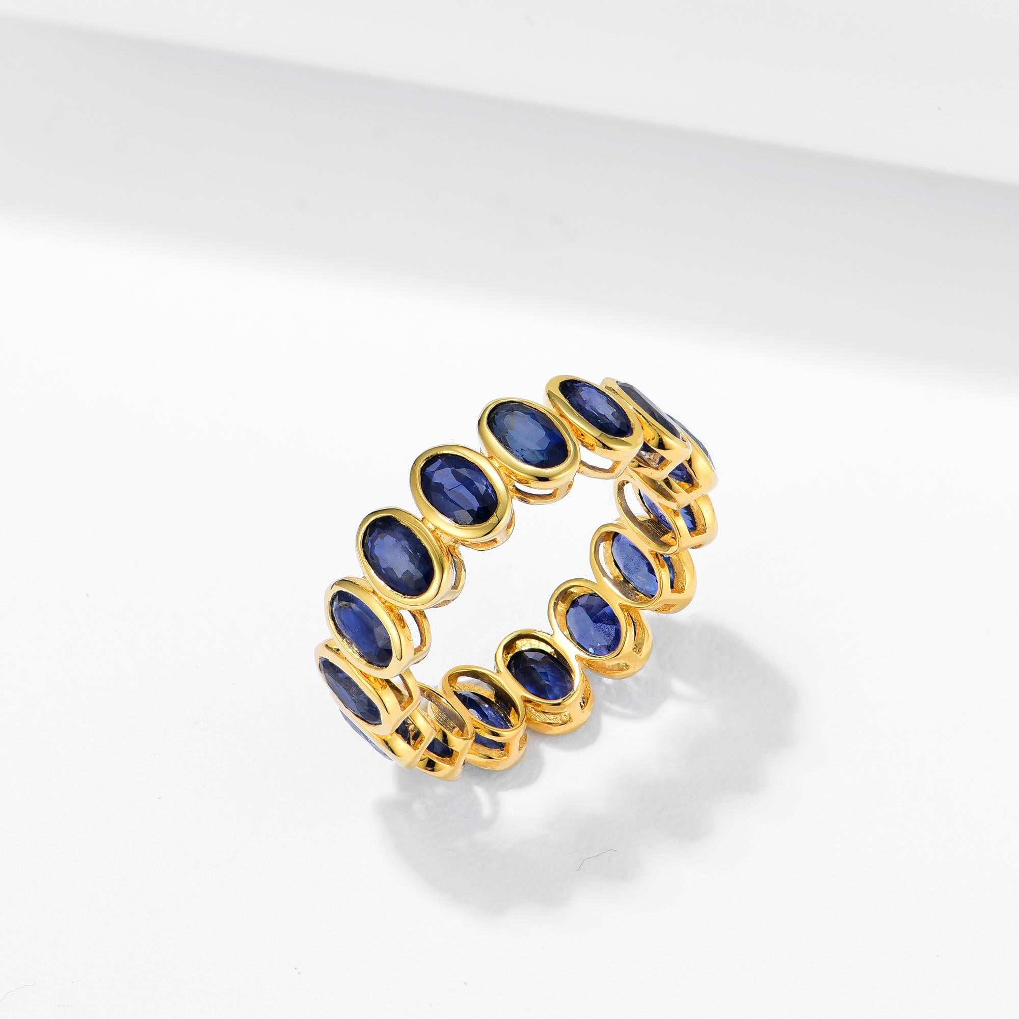 Embrace timeless elegance with the Nina Zhou Royal Blue Oval Sapphire Eternity Band, expertly crafted in luxurious 18k yellow gold. This stunning band showcases a continuous line of royal blue oval-cut sapphires, each meticulously hand-set to