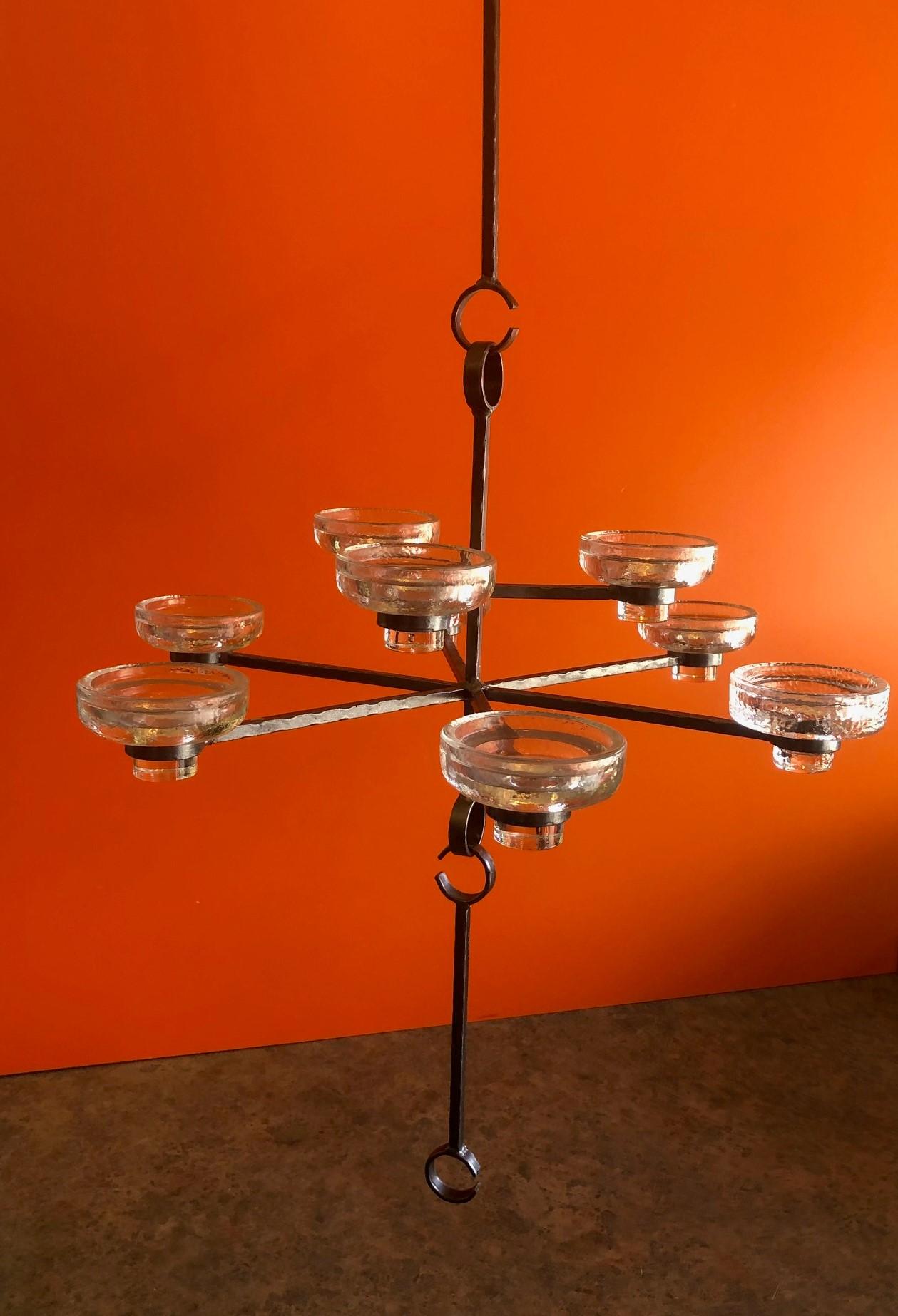 Gorgeous nine-candle chandelier by Erik Hoglund for Kosta Boda, circa 1960s. The chandelier which is made of wrought iron and glass was designed and manufactured in Sweden. 

There are nine glass candle holders (that measure 2