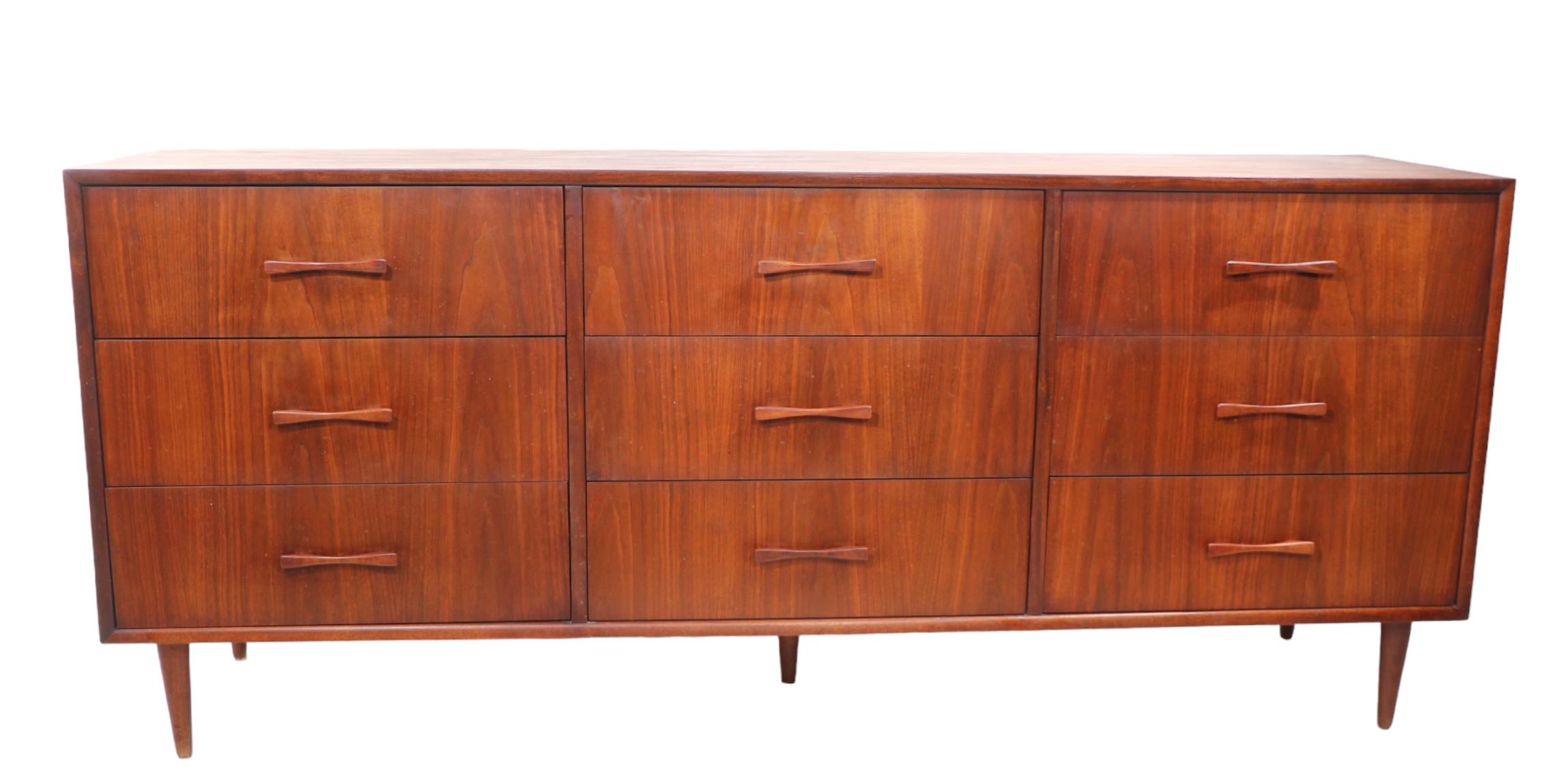 Large Mid Century Modern nine drawer dresser, having three banks of three drawers, each with a  solid wood sculpted bowtie form handle. The dresser provides ample storage, and is in good, original  vintage estate condition. 
 Specific condition