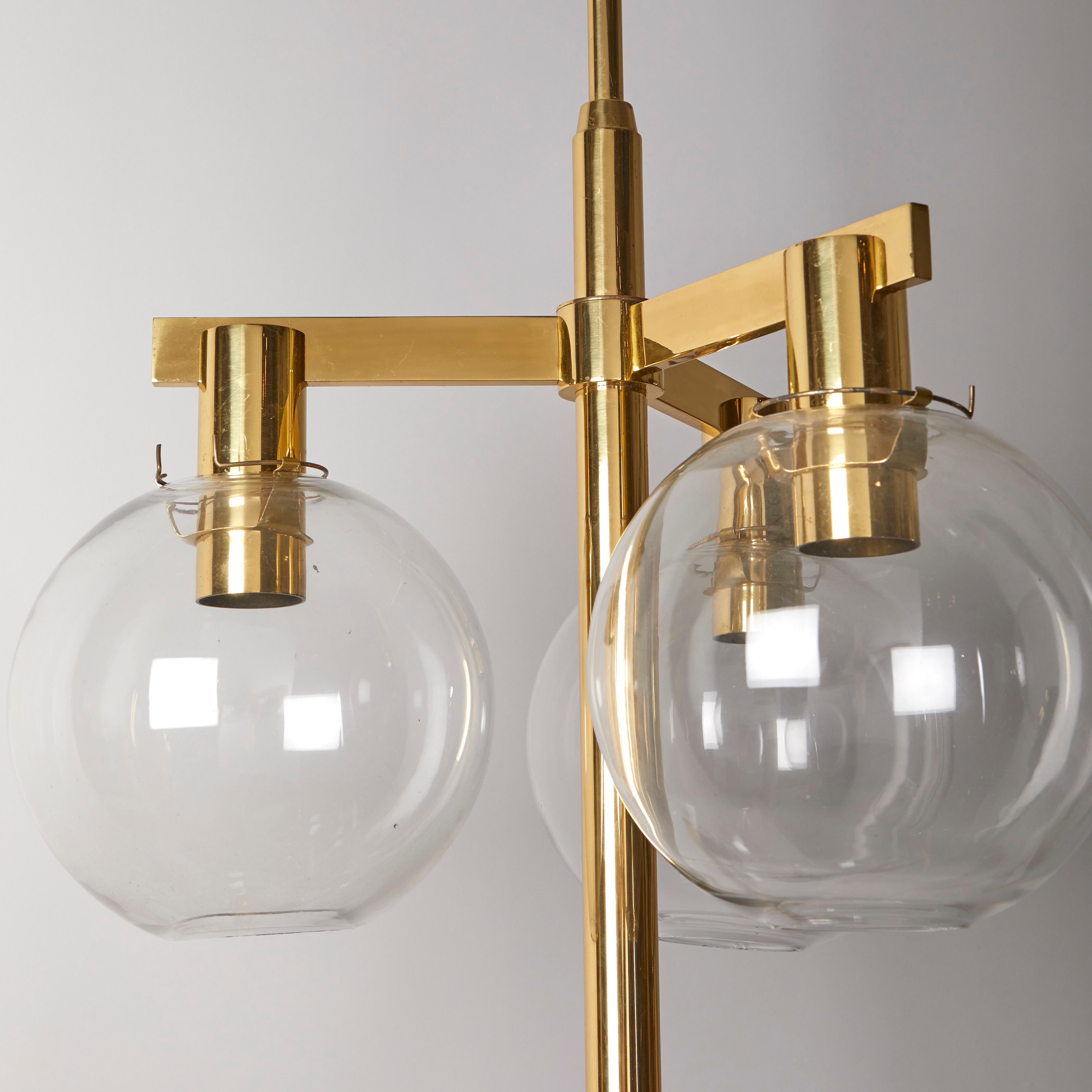 Un raro set di tre lampadari a nove luci di design contemporaneo disegnati da Hans-Agne Jakobsson (1919-2009). Le cornici in ottone con patina chiara e finitura laccata sono dotate di globi in vetro trasparente, ognuno dei quali nasconde una presa