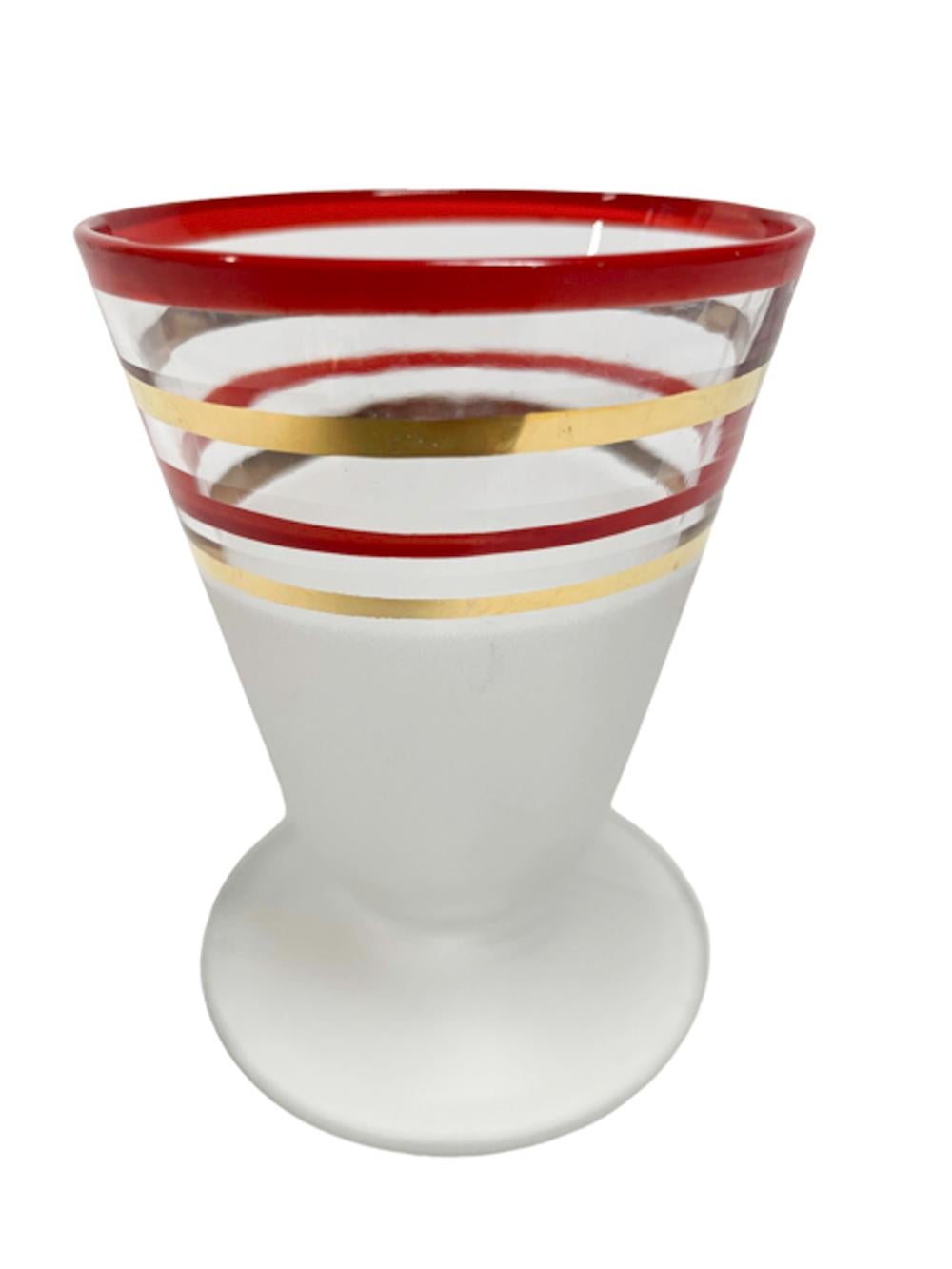 Nine piece Art Deco cocktail shaker set, cocktail shaker and 8 footed cocktail glasses with cone shaped bowls. Each piece decorated with red enamel and 22k gold bands on clear glass above frosted lower section.