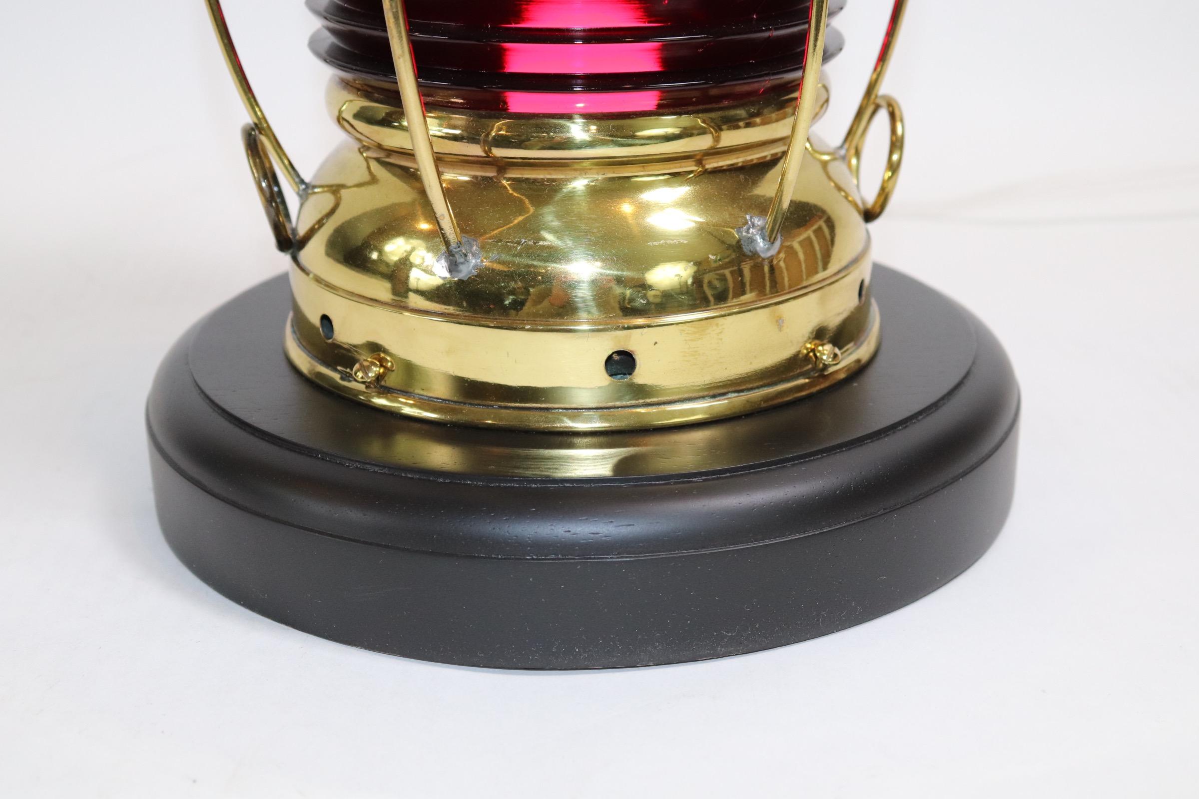 19th century solid brass ships lantern with highly polished and lacquered finish, rich ruby red lens and custom made wood base with rich dark finish. Wired for home display. Weight is 9 pounds.