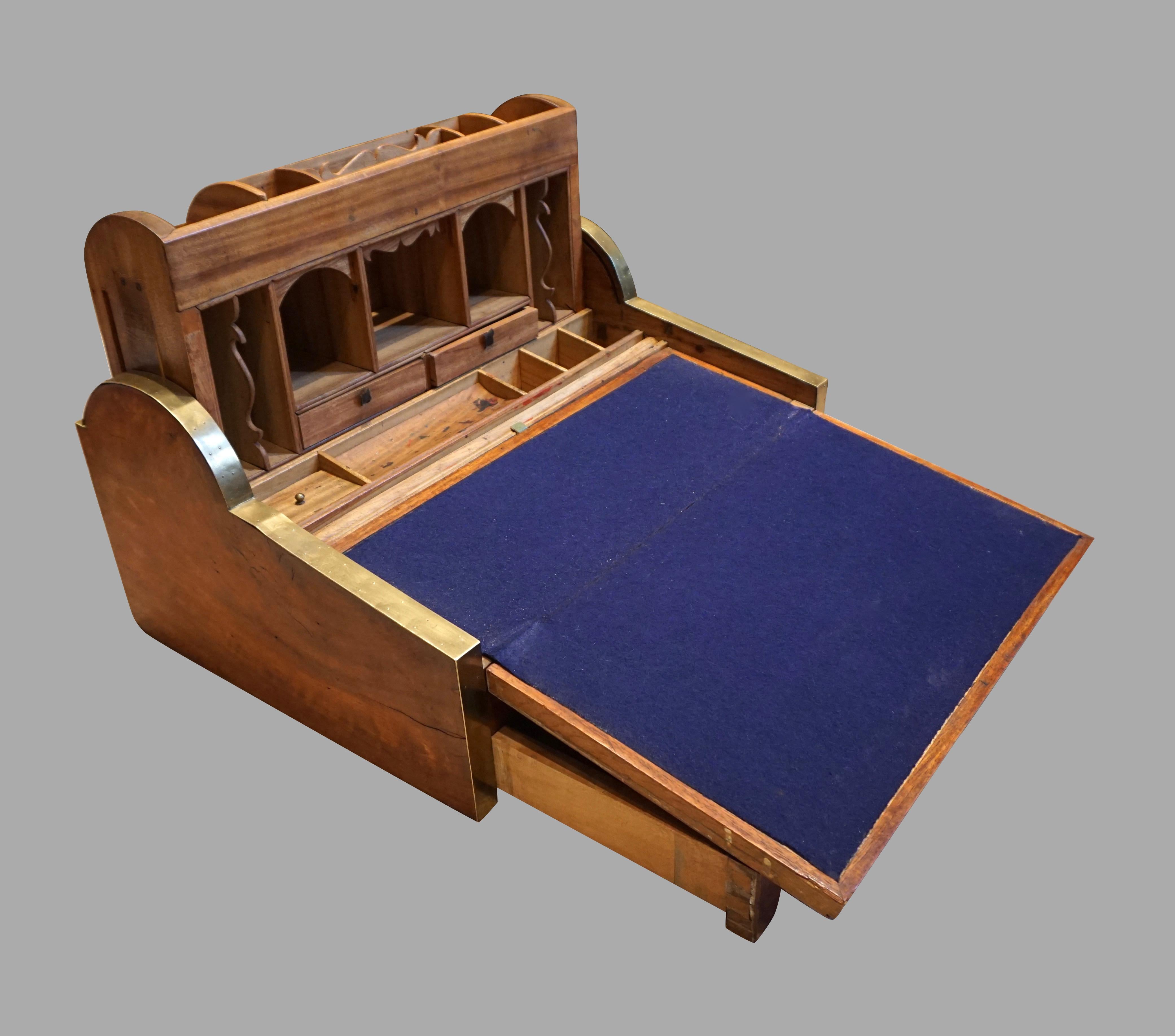 A Chinese export solid camphorwood brass inlaid and banded writing slope, the tambour activated by retracting the central drawer to reveal a rising section containing a variety of small drawers and cubby holes, the sloped writing surface lined in