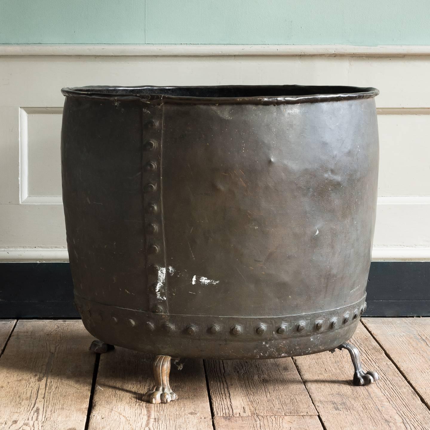 A substantial English 19th century patched and riveted copper with brass lion's paw feet, suitable for use as a log bin or a planter.