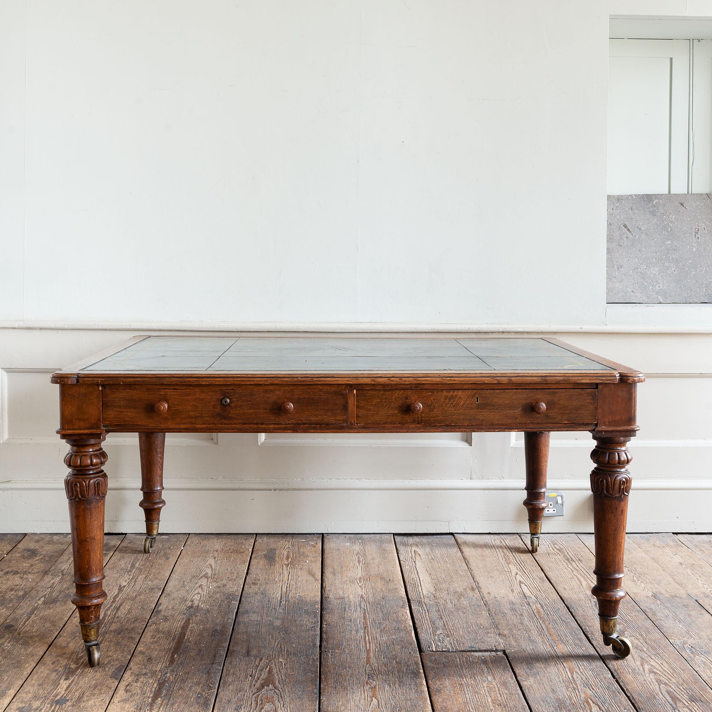 A Nineteenth century Holland & Sons library table, circa 1830s, oak with gilt-tooled leather skiver, raised on lambrequin carved turned and tapered legs, with brass castors.

Dimensions:	75cm (29½