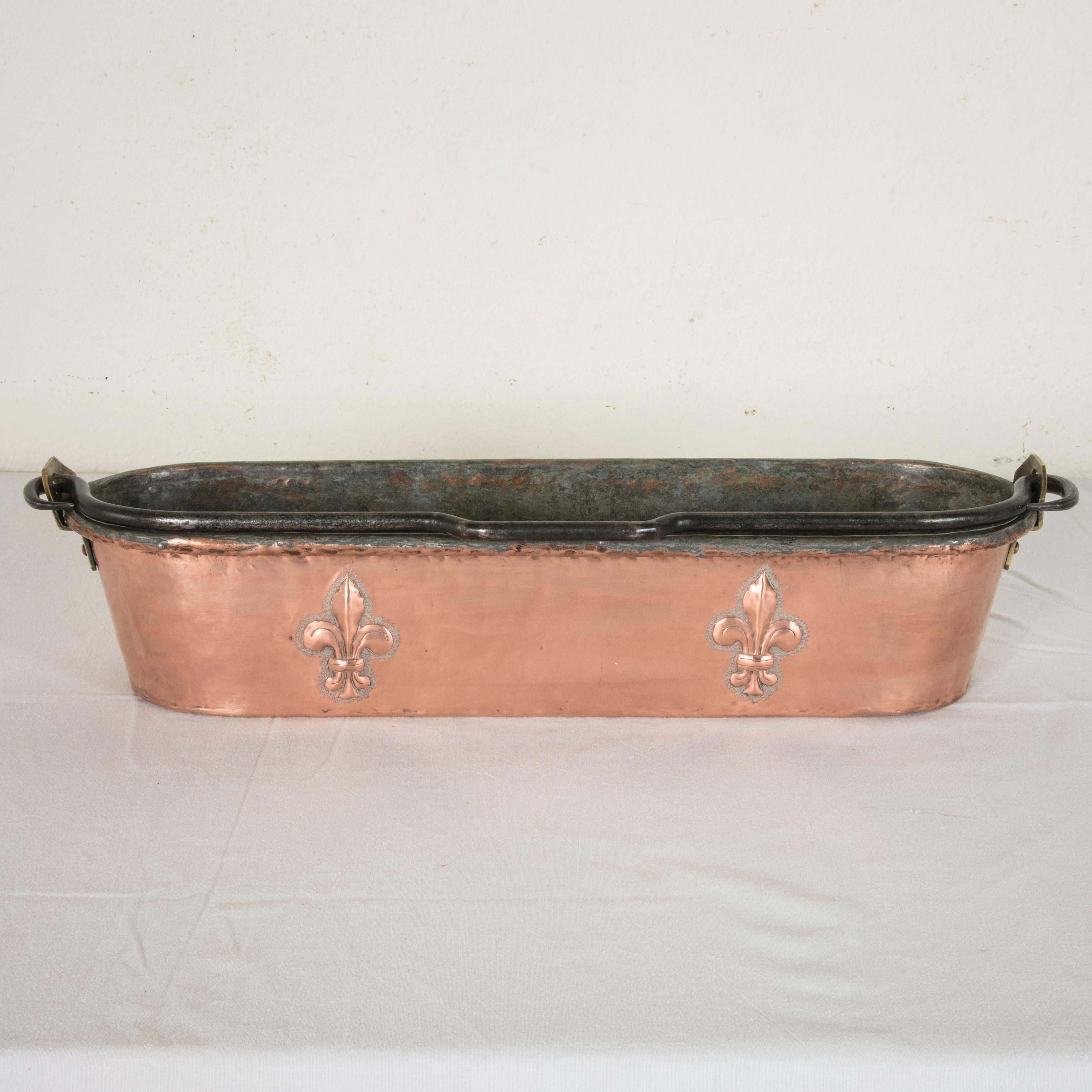 Originally used in a French chateau, this Louis Philippe period copper poissoniere or fish poacher from the 19th century features two repousse fleurs-de-lys on each side. An iron handle is held by copper riveted bronze plates. A beautiful