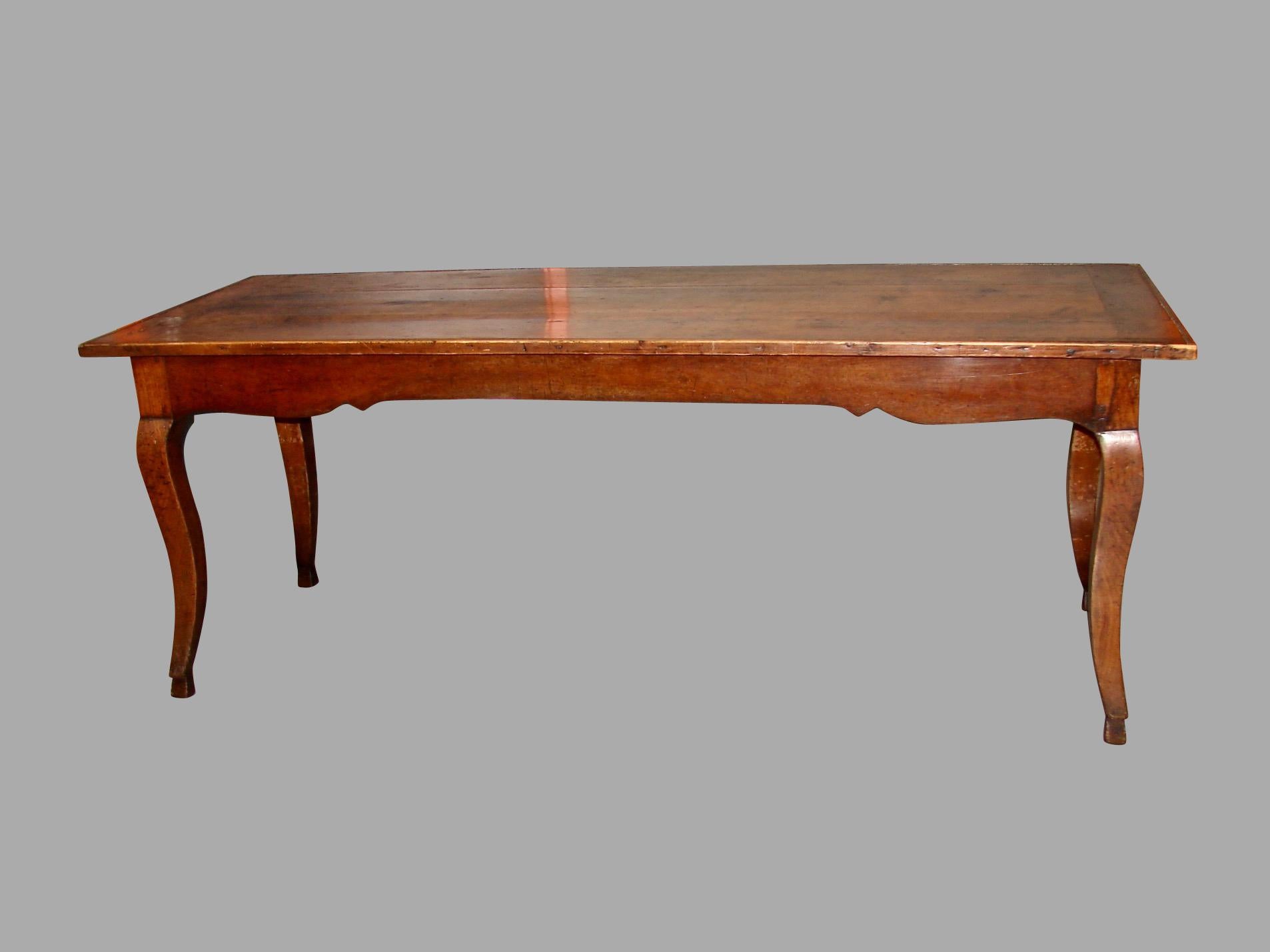 A good French fruitwood farm table with a breadboard top and scalloped apron resting on cabriole legs ending in hoof feet. The piece has peg construction throughout, with a single long cutlery drawer at one end. Lovely old color and patina, circa