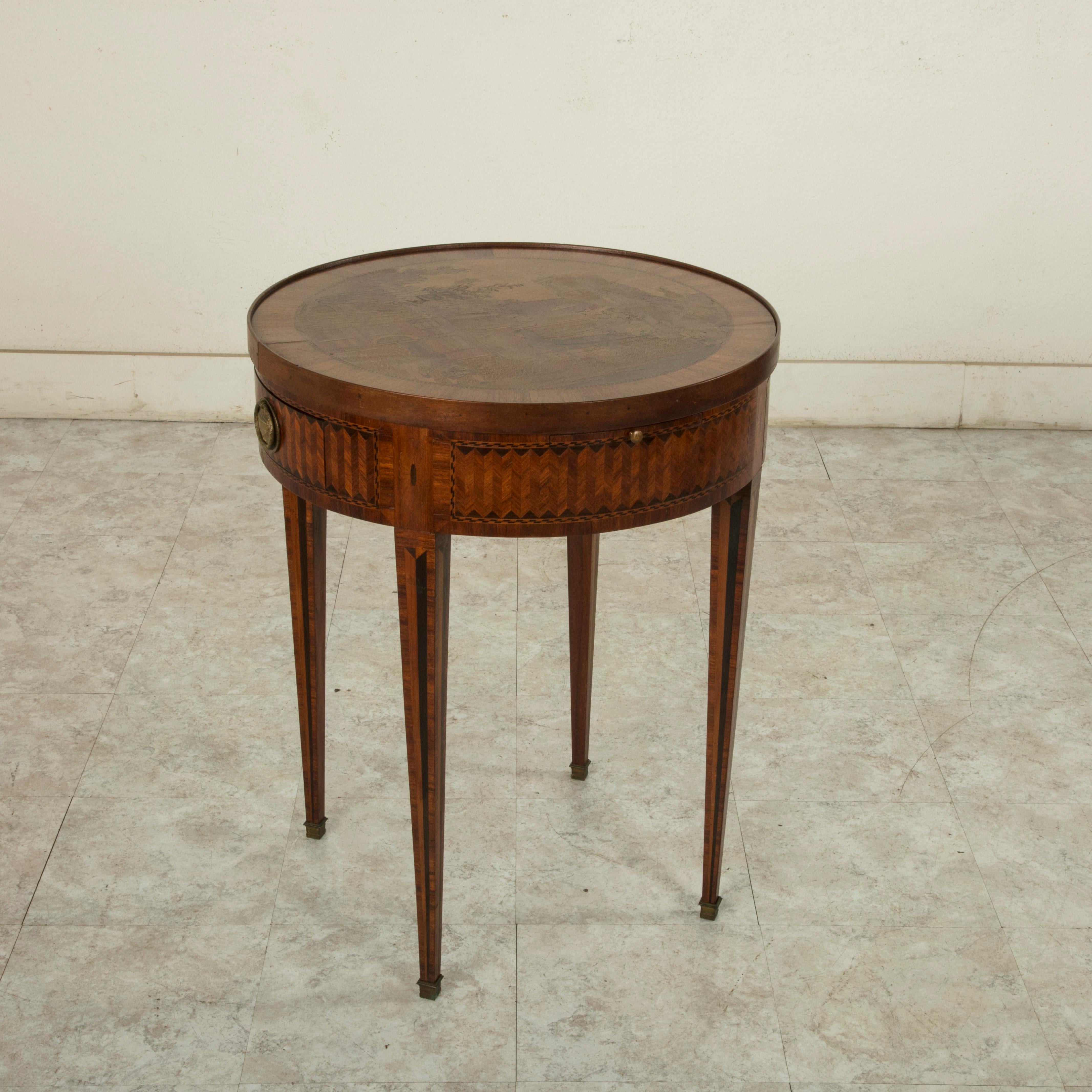 A unique game table from the late 19th century, this Louis XVI style marquetry table features a removable top. A marquetry genre scene of a horse drawn carriage making its way through a village is on one side, and a checker board is on the reverse