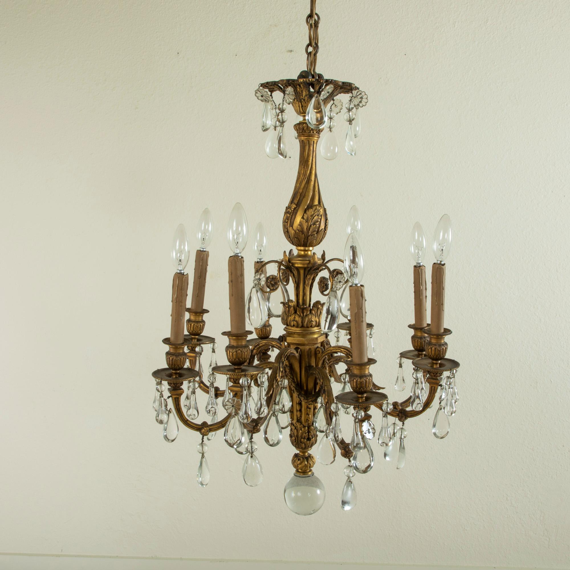 This mid-nineteenth century French Napoleon III period solid bronze chandelier features large crystal teardrops that hang from its eight arms. The central spiral fluted bronze pillar is detailed with acanthus leaves and garlands and a large crystal