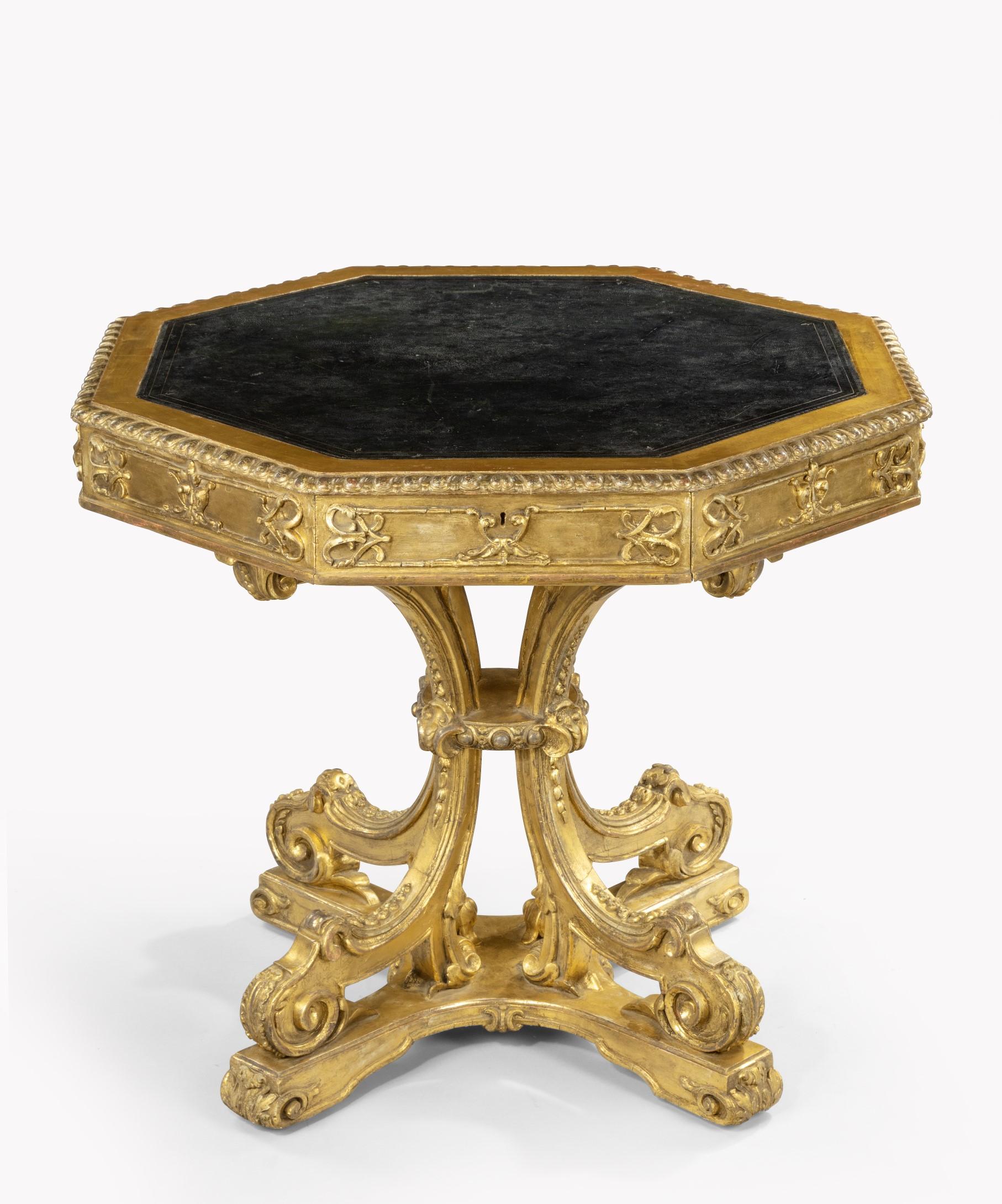 An unusual early 19th century carved giltwood octagonal drum table; the drum table's leathered top with a carved gadrooned edge above four frieze drawers decorated with carved strapwork. The table's drawers are cedar lined, a great sign of quality,