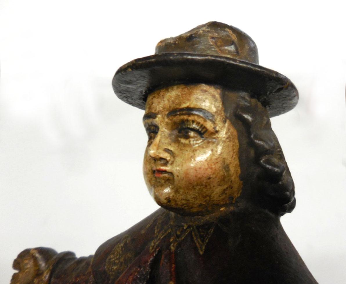 This 19th c. Spanish colonial Nino de Atocha is carved out of one piece of wood. The Nino de Atocha is a Roman Catholic image of the Christ child and he protects travelers from danger and usually holds a basket and a staff, both missing here.