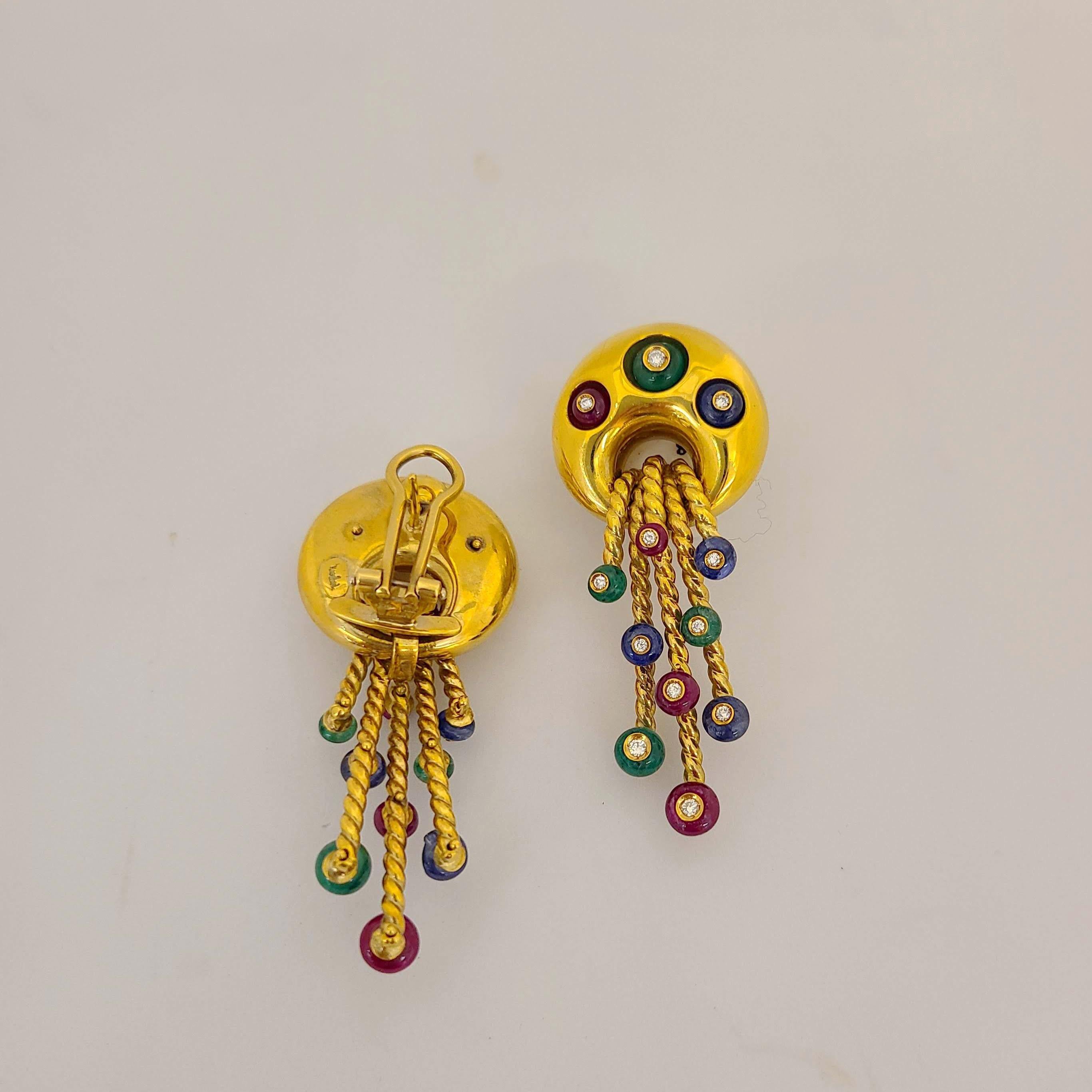 These 18 karat yellow gold earrings were designed by Nino Verita of Italy. A hi polished button earring with 5 stationary gold strands  are accented with emerald, ruby,and sapphire beads. Each bead is set with a round brilliant diamond. The earrings