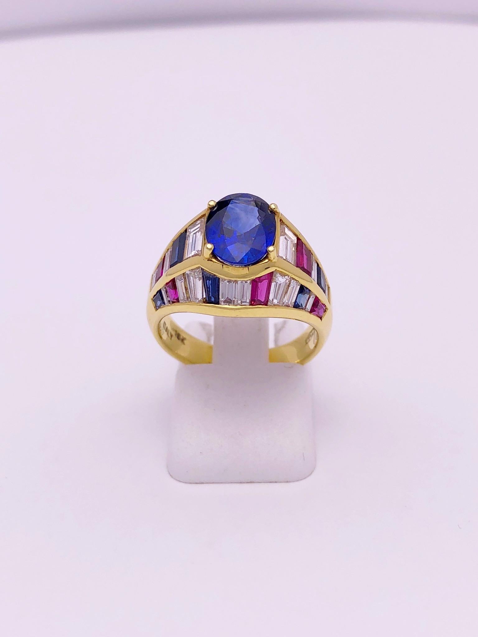 This 18 karat yellow gold ring was designed by Nino Verita of Italy. The setting alternates bagutte cut stones of diamonds, rubies, and blue sapphires set in a pyramid style setting. The center stone is an oval blue sapphire.
Center sapphire 2.30