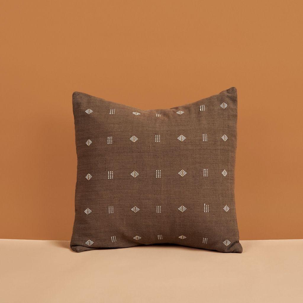 L'oreiller Nira Choco est un coussin tissé à la main légèrement texturé où nos artisans ont habilement créé un motif classique à l'aide d'une ancienne technique de tissage. Le fil non teinté est utilisé comme élément de conception avec des toiles de
