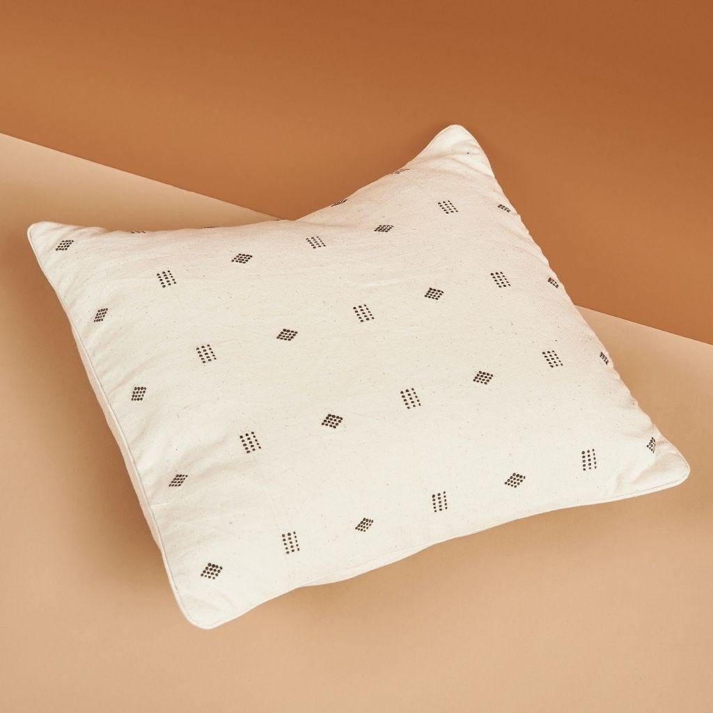 Nira White Pillow s a slightly textured handwoven pillow where our artisans have skillfully created a classic pattern using an ancient weaving technique. Undyed yarn is used with the black design elements that minimally stand out The dyes are