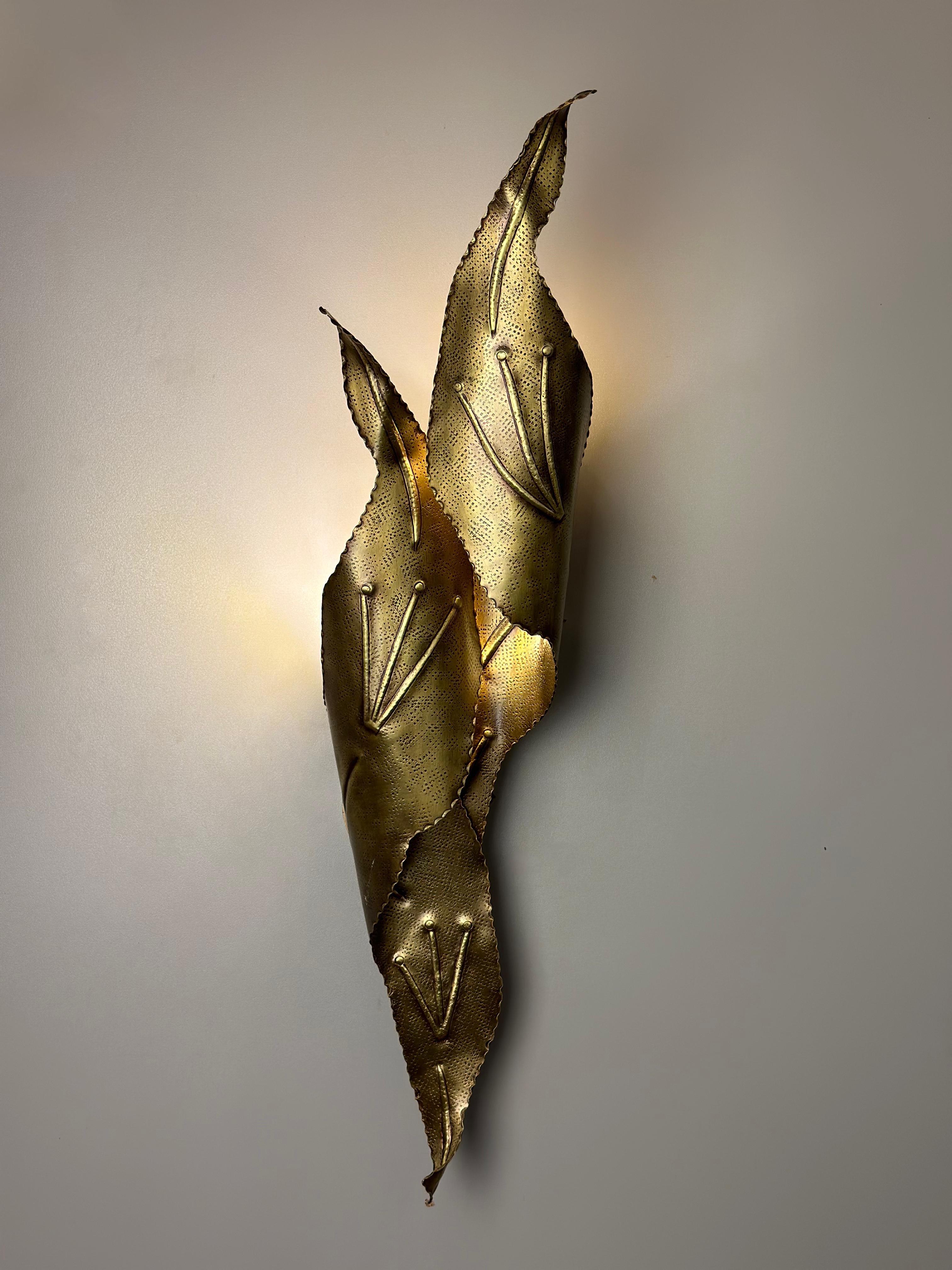 Enrich your living space with the enchanting allure of NISIA, a captivating brass hammered wall sconce that seamlessly melds the elegance of nature with meticulous artisan craftsmanship. Crafted with utmost care, NISIA features two gracefully curled