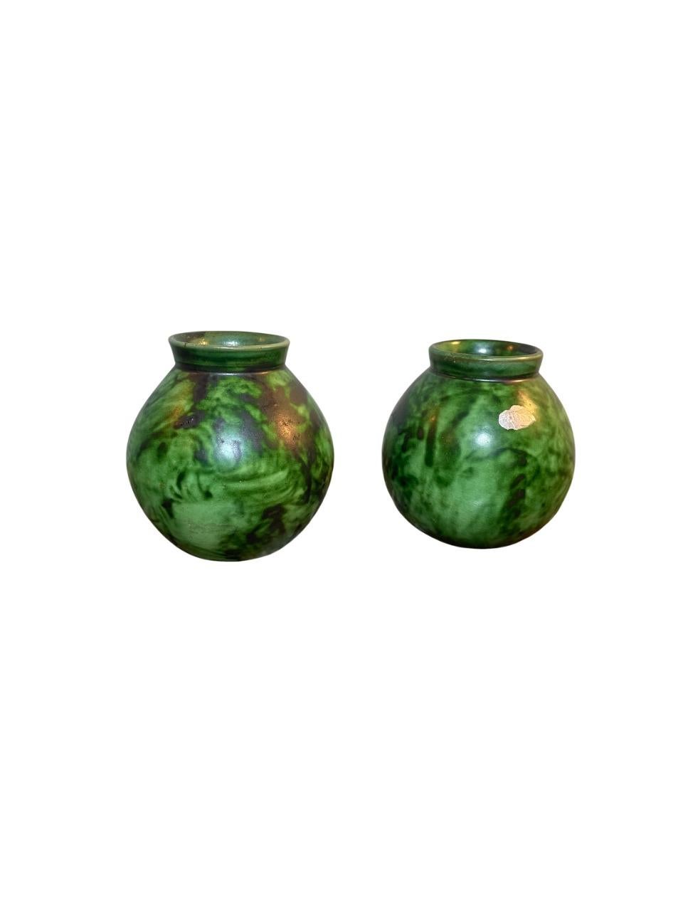 Un affascinante trio di vasi sferici in ceramica disegnati da Erik Mornils per Nittsjö Keramik, Svezia, circa 1930. Questi vasi, lavorati a mano, presentano un ricco smalto verde screziato con sottili variazioni di tono e profondità, caratteristiche