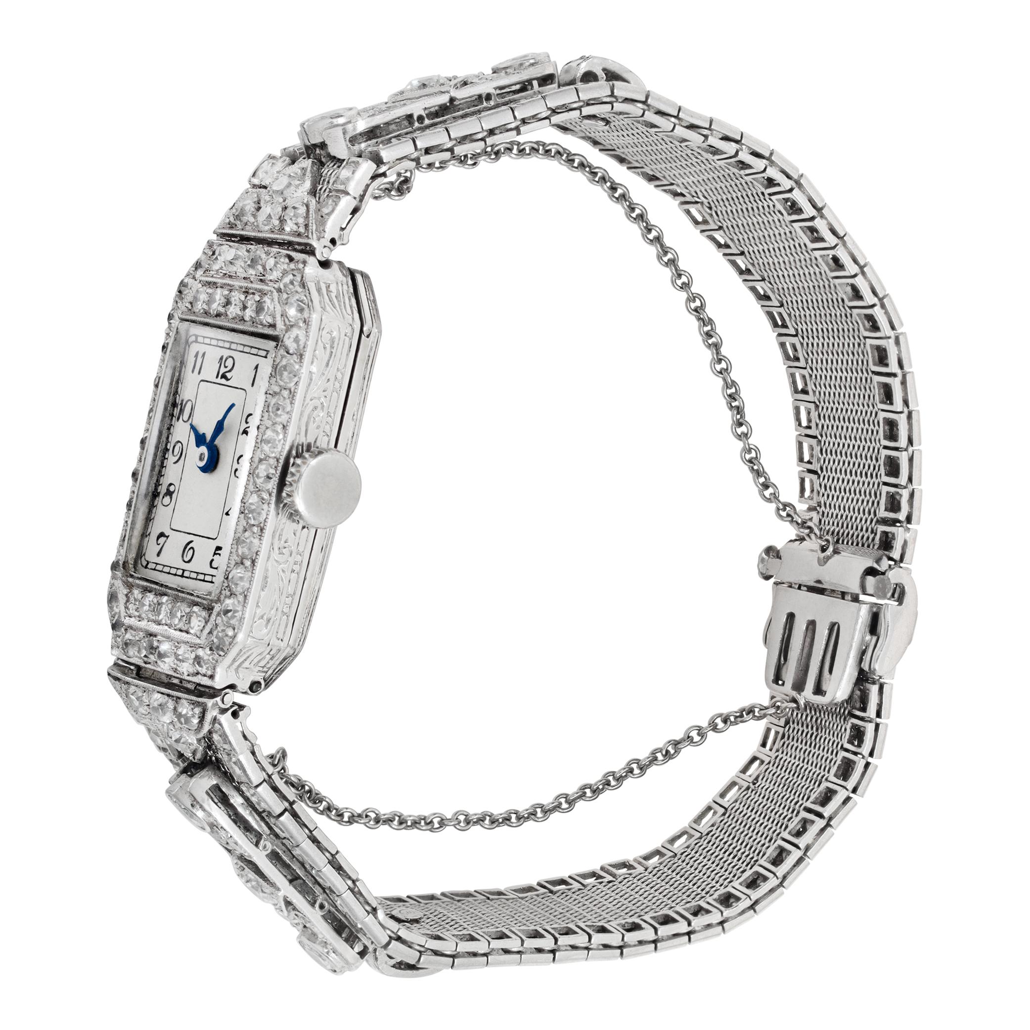 Reloj de cóctel Nivia Swiss Classic de 15 joyas en platino con aproximadamente 2 cts de diamantes de color F-G y claridad VVS-VS. Movimiento manual de 15 joyas. Art Decó, hacia 1920. Mide 25 mm de largo de orejeta a orejeta por 15 mm de ancho. Ref