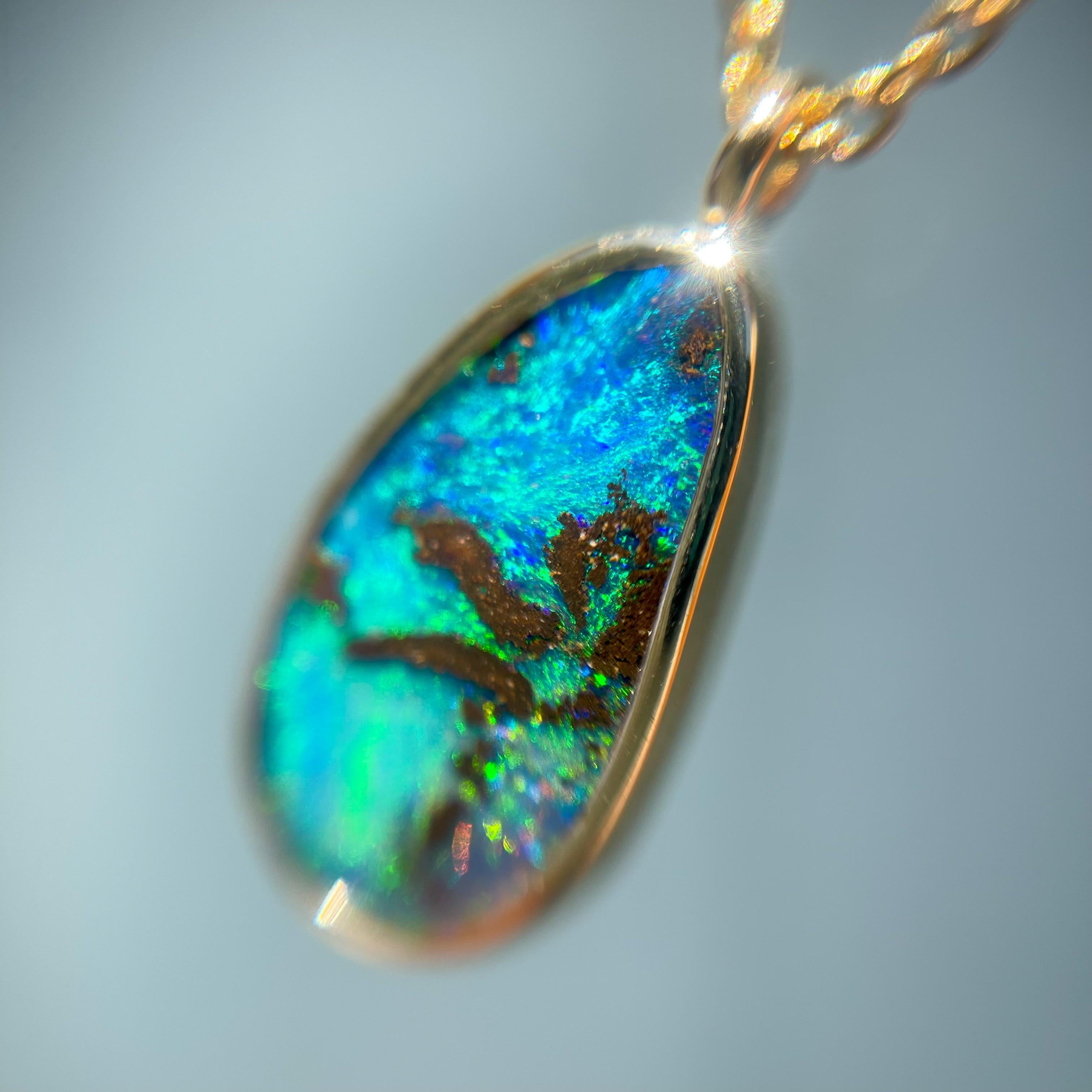 A stunning Australian Opal Necklace evokes the essence of summer. Superimposed upon the natural opal is the likeness of a palm tree atop electric greens and blues. The dark silhouette creates a striking contrast against the intense color gradient of