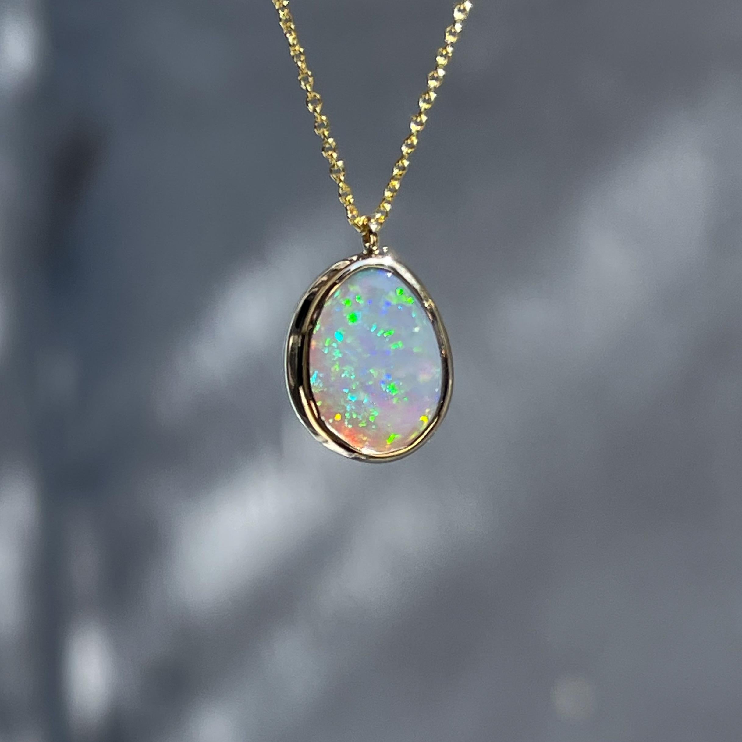 Flecks of sunset and shimmering green spark against the misty grey backdrop of this Australian Opal Necklace. Beautifully neutral, the Lightning Ridge Opal makes a stunning canvas for the contrasting colors. Framed in yellow gold, and mounted in a