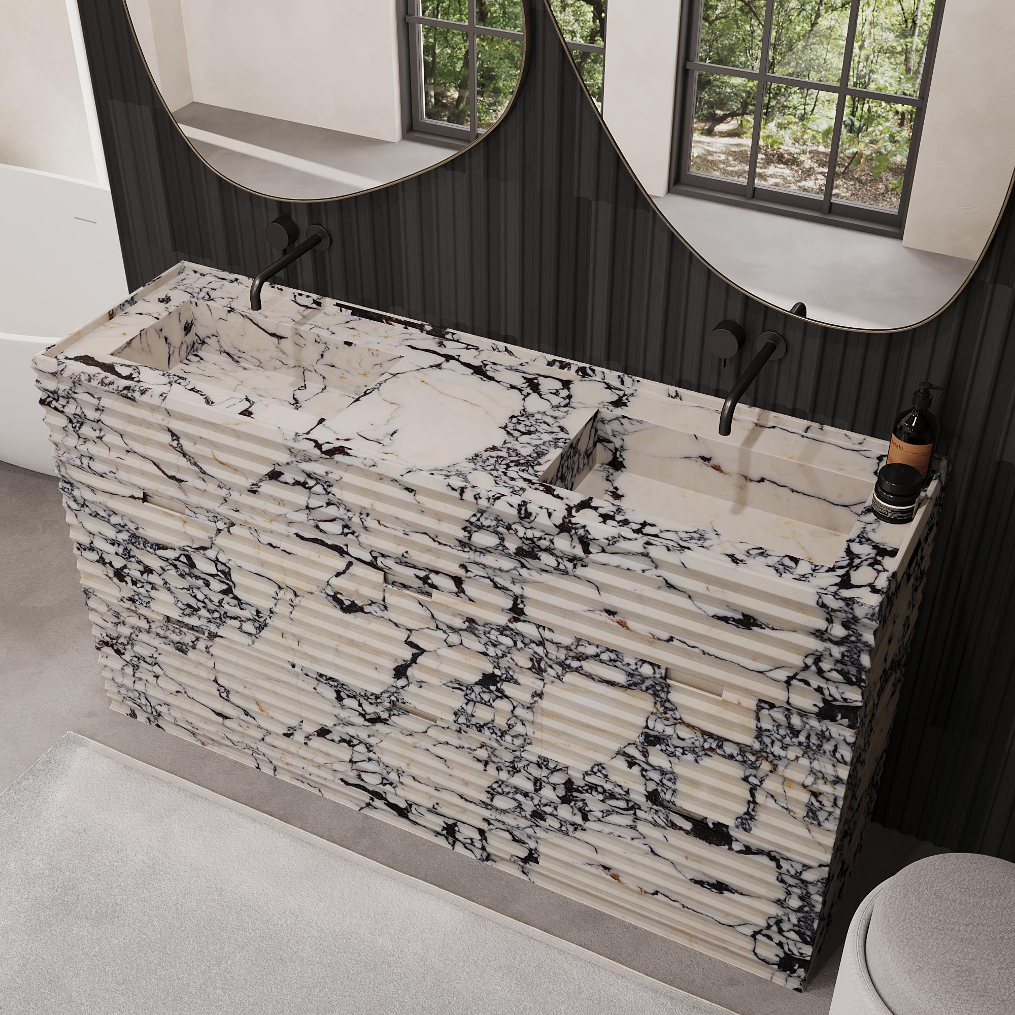 Améliorez votre salle de bain avec notre luxueux meuble-lavabo en marbre à deux vasques Njord, dont la texture joliment nervurée ajoute de la profondeur et du caractère à l'esthétique de votre salle de bain. L'extérieur est entièrement fabriqué en