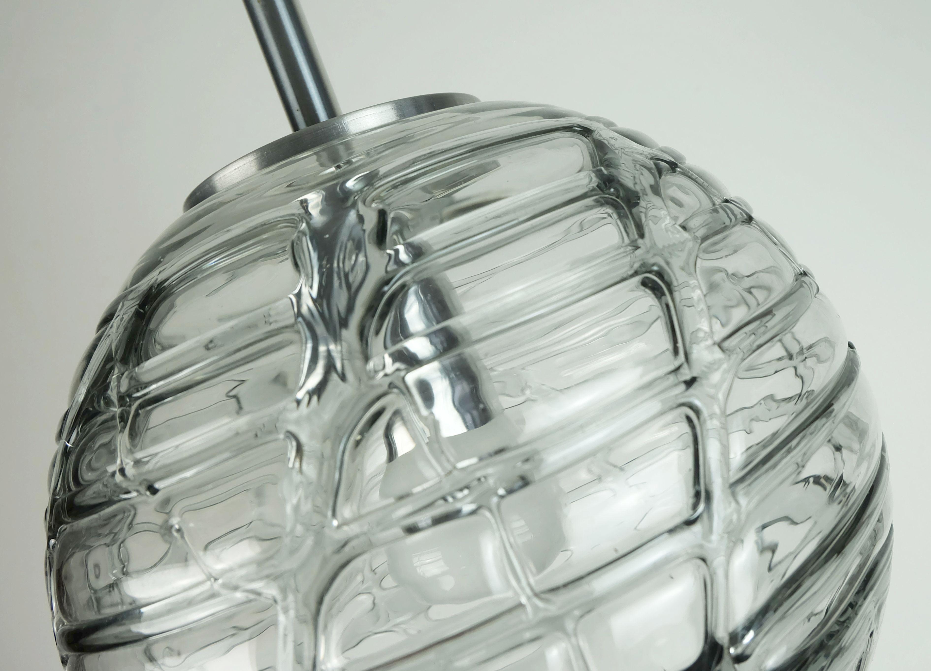 Una bellissima ed elegante lampada a sospensione degli anni '60/'70 di Doria Leuchten, Germania. Vetro trasparente e vetro grigio fumo con superficie strutturata. La montatura è realizzata in metallo color argento con finitura opaca spazzolata, filo