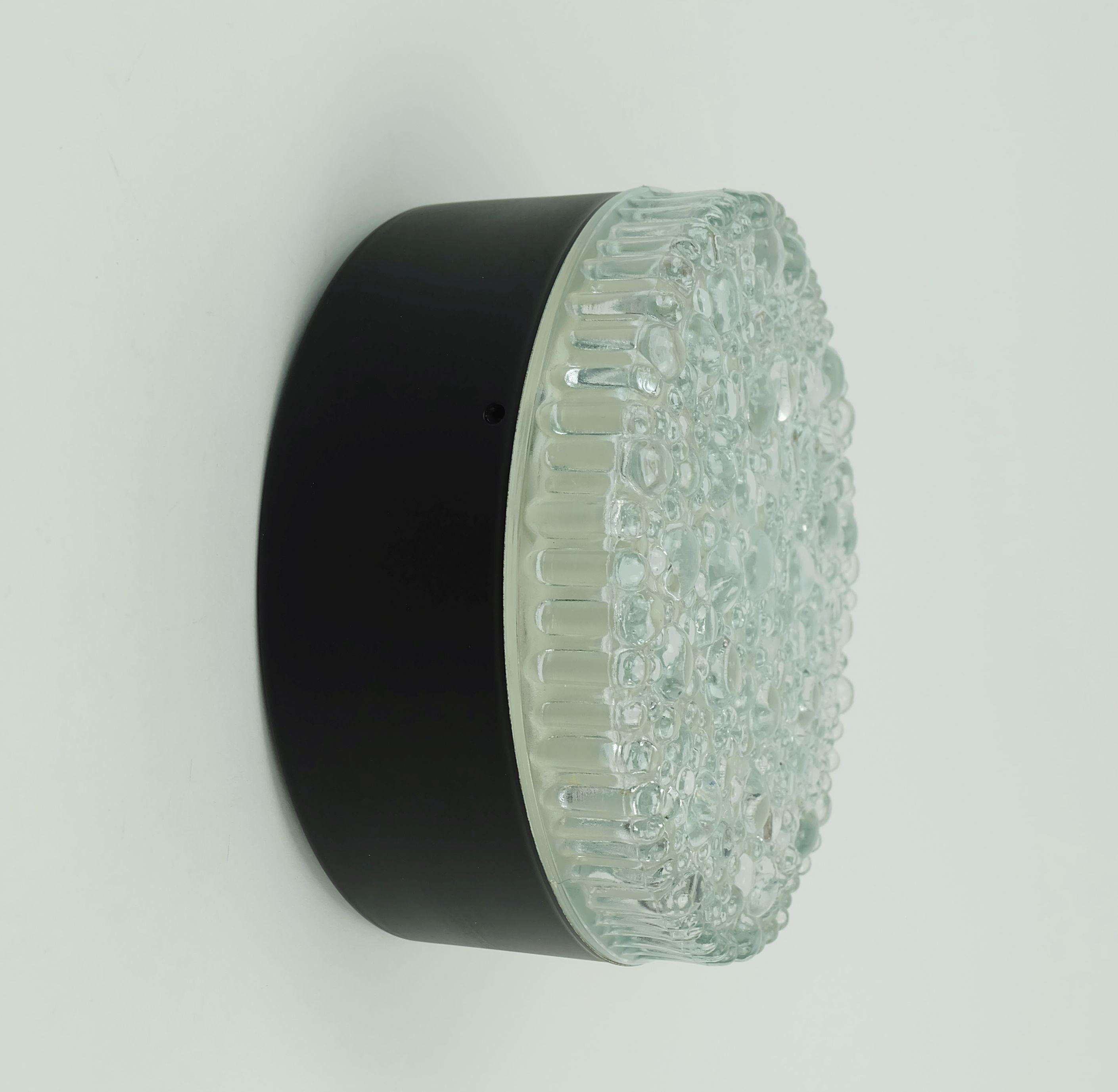 Round ceiling light from the 1960s/70s. By Staff, West-Germany, model no. A 226. Ceiling mount made of matte black painted metal, shade made of textured glass with a bubble finish. For one E27 bulb. Can also be used as a wall lamp. 

Another