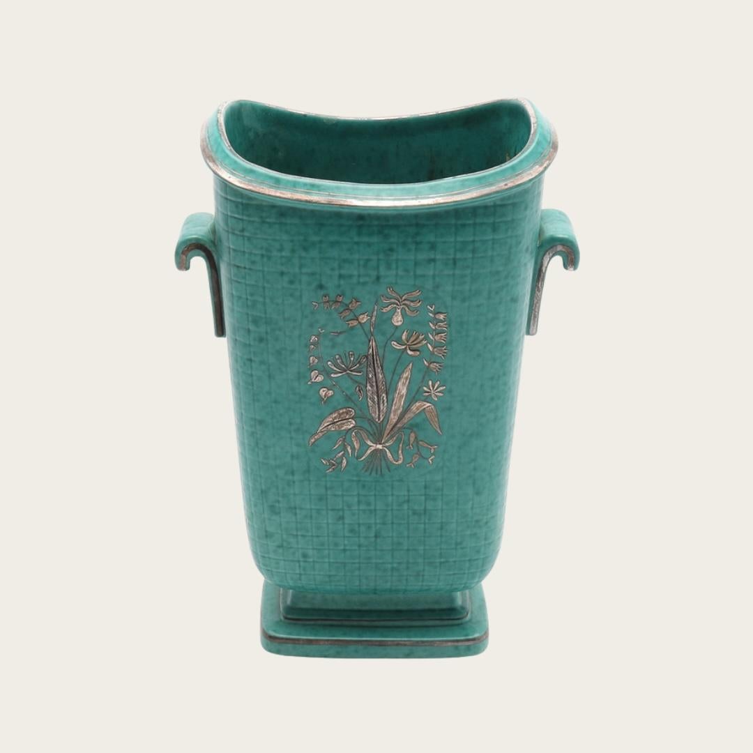 Années 1940, Suède. Vase à large ouverture avec des poignées décoratives par Wilhelm Kåge de sa collection Argenta de grès produit pour l'usine de Gustavsberg. Glaçure turquoise mouchetée avec des détails de feuilles d'argent représentant des fleurs