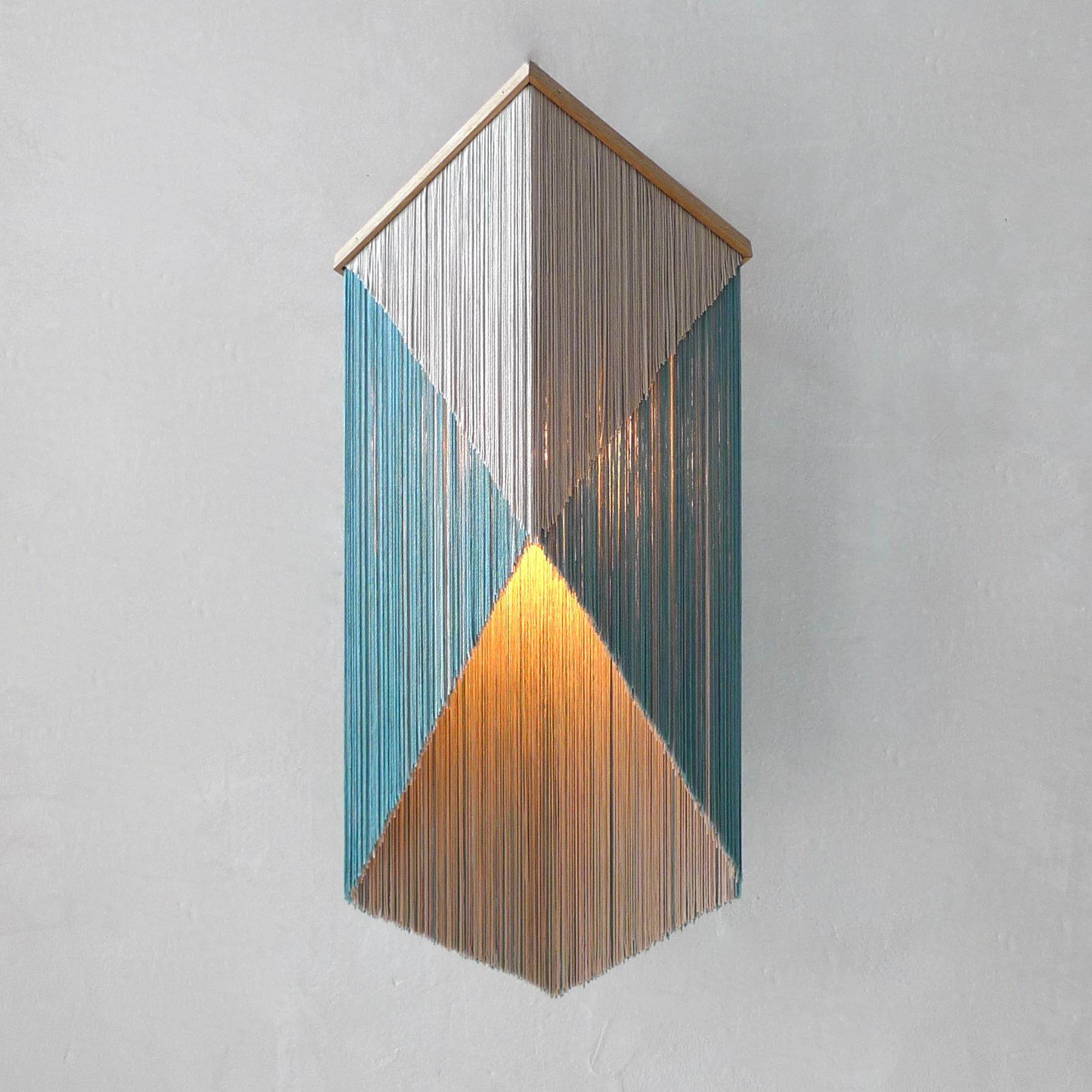 No. 28 wall lamp by Sander Bottinga
Dimensions: H 46 - 70 x W 31 x D 22 - 30 cm
Materials: Brass, Wood, Leather, Viscose Fringes
Variations available.

Handmade in brass, wood, leather and 3 double layered viscose fringes in
geometric cut and