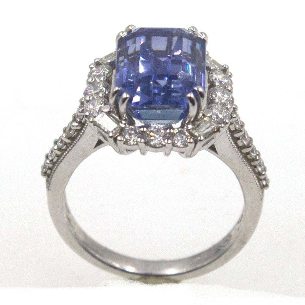 This beautiful sapphire diamond ring features a 7.34 carat Natural Ceylon Sapphire surrounded by 1.50 carats of round brilliant cut diamonds. The gorgeous violet blue sapphire is an emerald cut that measures 11.6 x 8.3 x 7.0mm and has been certified