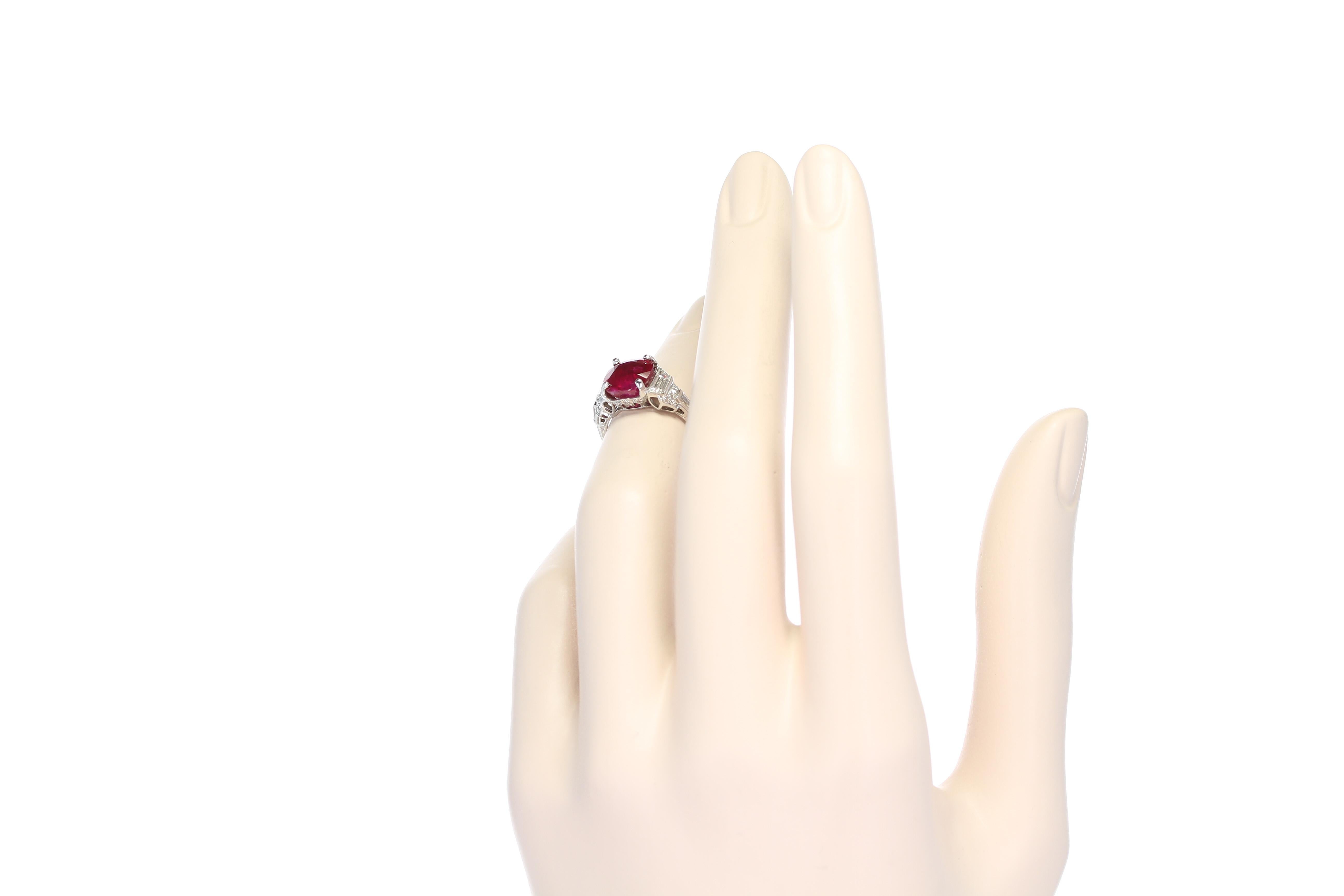 A beautiful and vivid red natural cushion shaped ruby set with two trapezoid diamonds, two baguettes and twenty-two small, round brilliant-cut diamonds, set in Platinum. The ruby weighs 4.23 carats and is accompanied by a gemological certificate