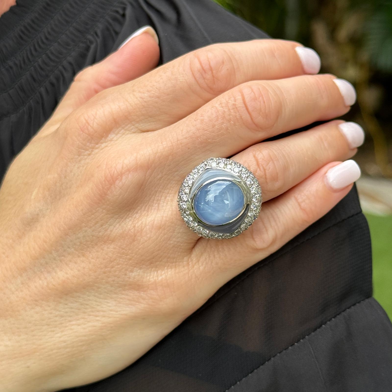 Stunning and unique star sapphire diamond cocktail ring crafted in 18 karat white gold. The ring features a natural no heat blue star sapphire gemstone weighing 20.37 carat certified by the GIA. The sapphire is flanked by two free form blue cabochon