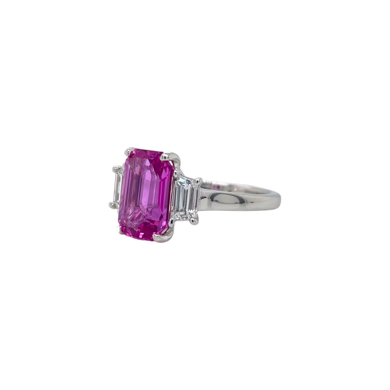 Ring contains one GIA certified no heat emerald cut pink sapphire 3.55ct and two side step cut trapezoid diamonds 0.68tcw. Pink Sapphire and diamonds are mounted in a handmade basket prong setting with a 2mm wide shank. Diamonds are F in color and