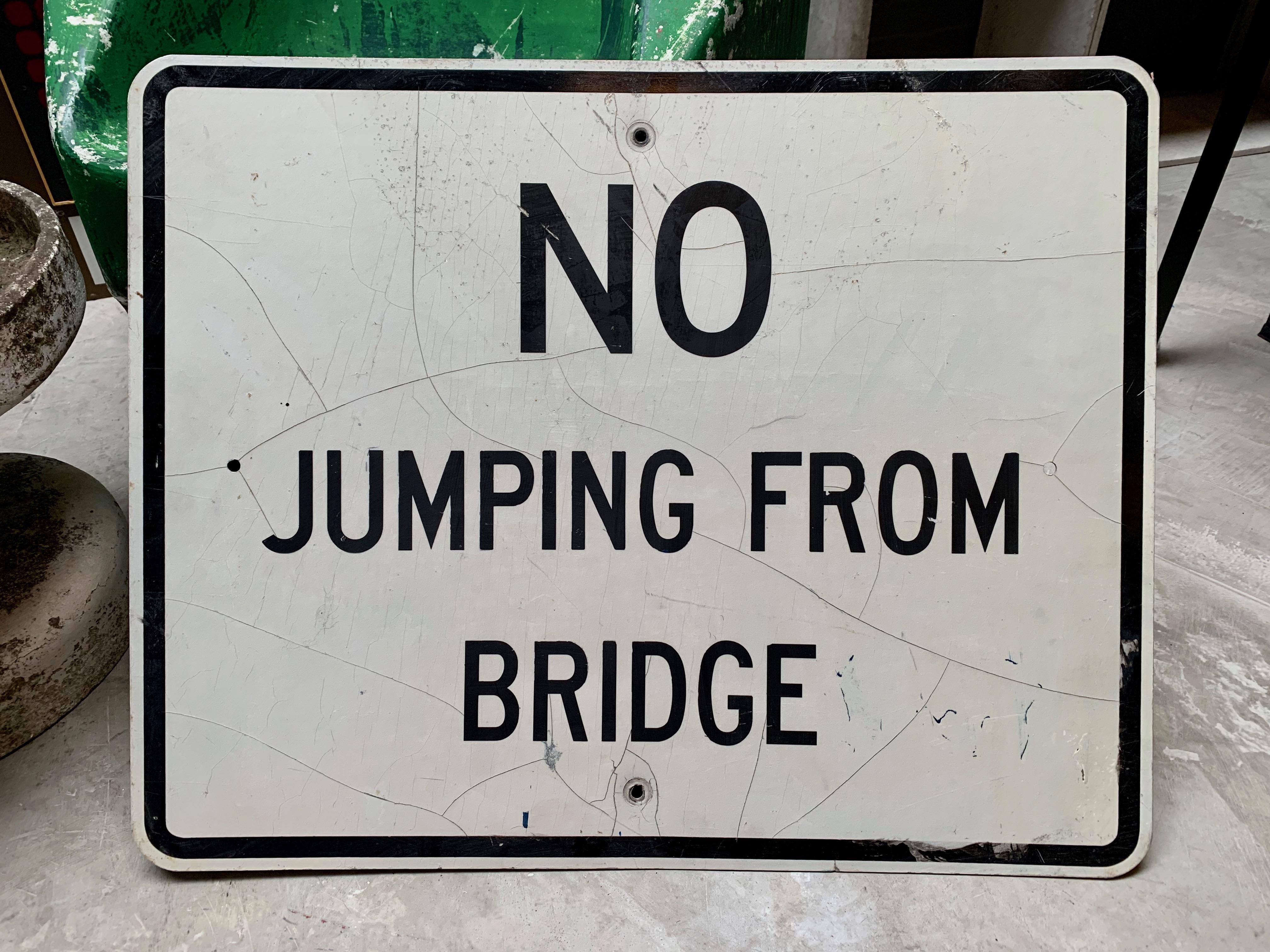 Rare vintage steel road sign warning people not to jump from the bridge. White sign with black lettering 
