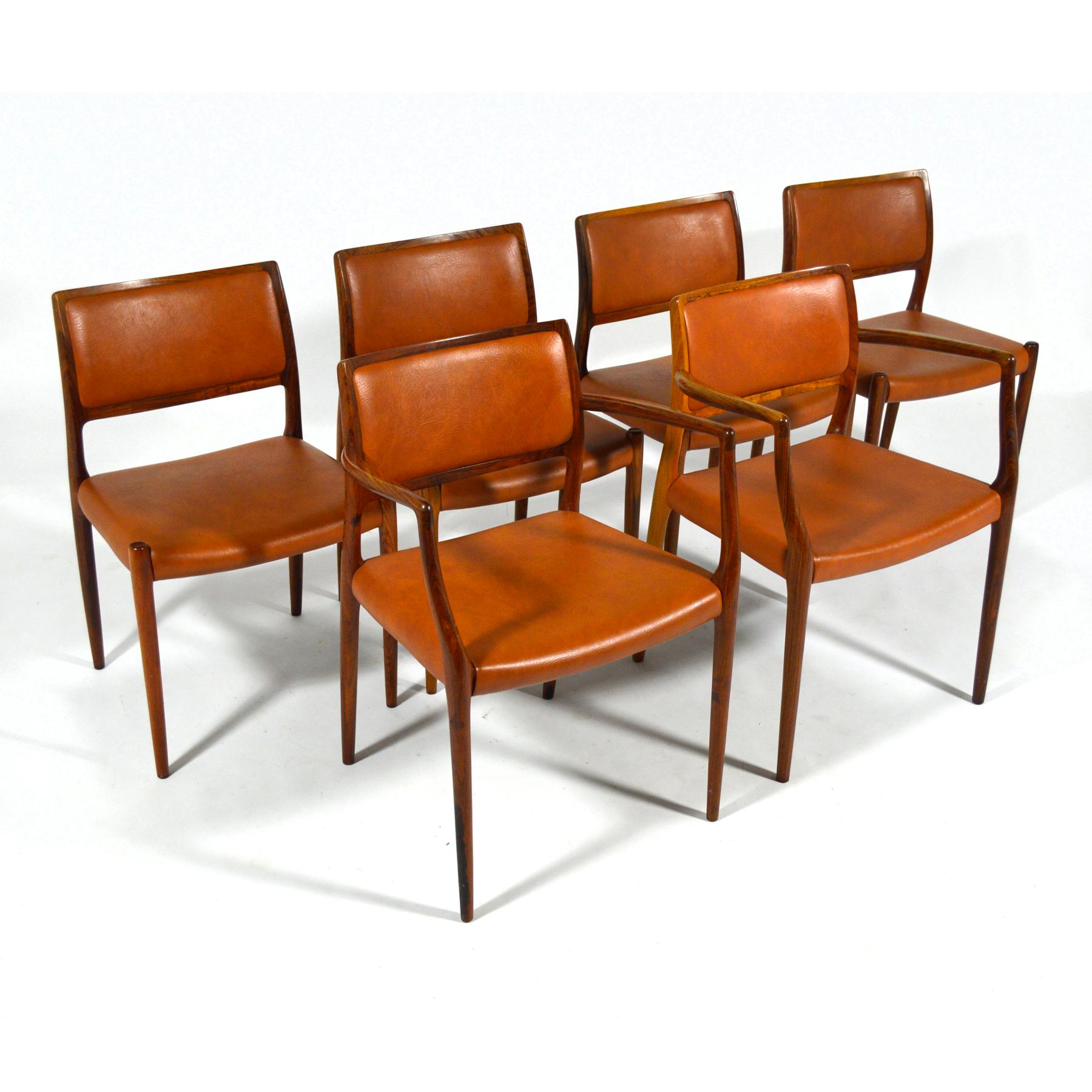 This beautiful set of dining chairs by Niels O. Møller for J.L. Møllers Møbelfabrik consists of four model 80 side chairs and two model 65 armchairs. The frames are sculpted of rich rosewood and they are upholstered in a lovely cognac colored